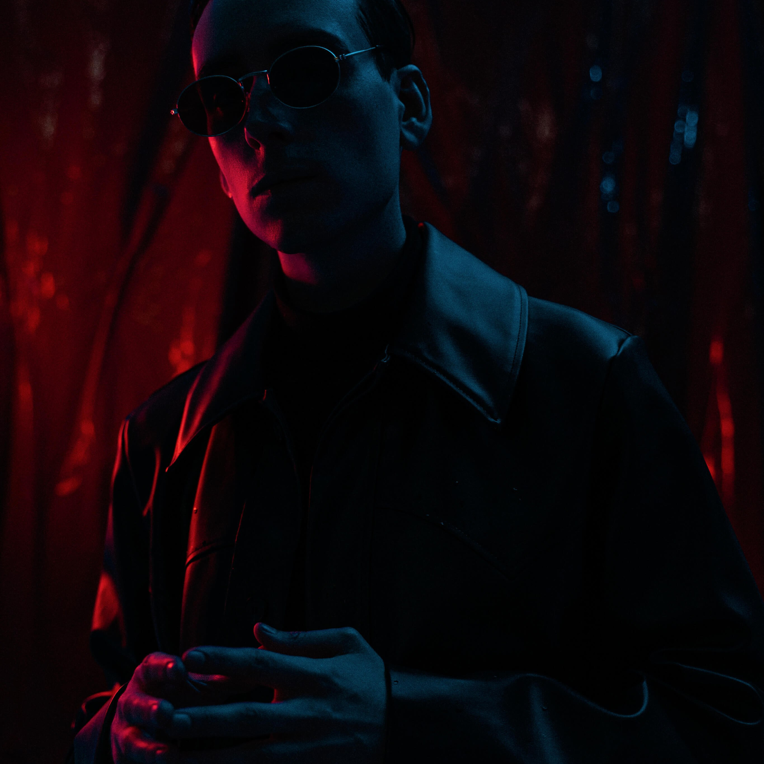 Haunting portrait of a man bathed in blue light, his silhouette set against a dark backdrop, evoking a noir mood