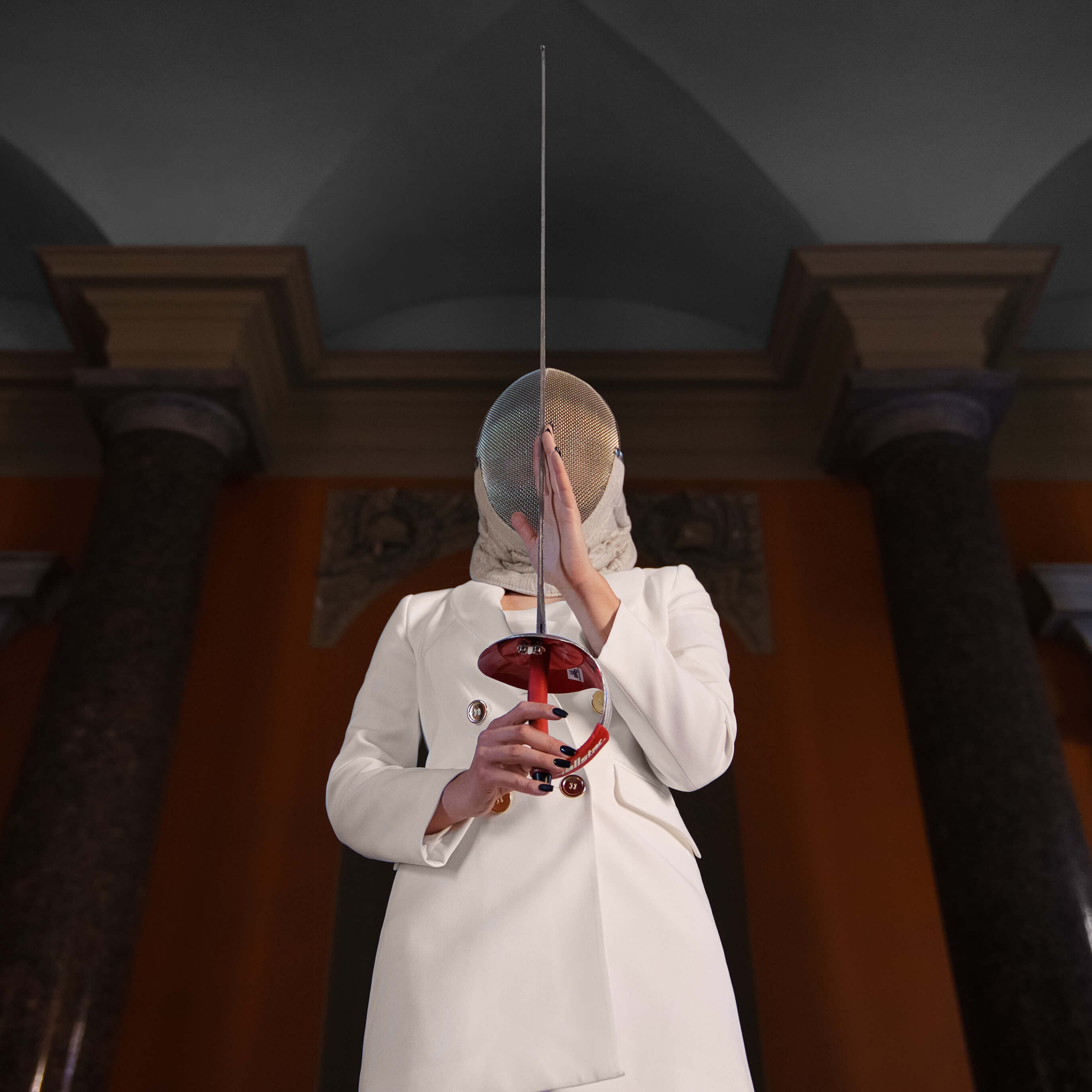 A conceptual portrait of a person in a white coat holding a fencing epee vertically in front of their face, blending with the symmetrical architecture of columns and arches in the background, creating an intriguing and harmonious composition