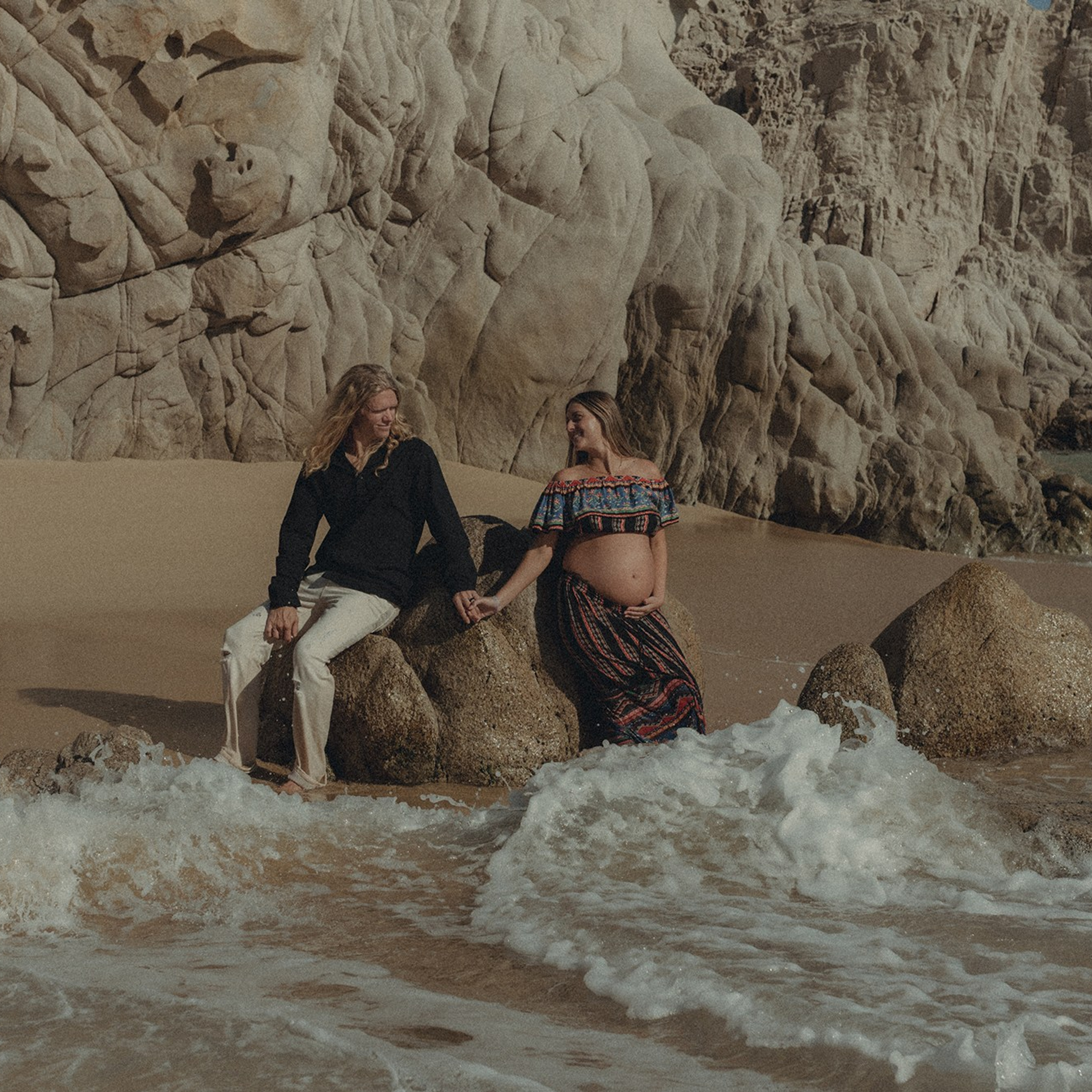 Maternity session in Los Cabos – expecting mother photographed at Playa del Amor with cinematic color grading, warm light, and the iconic Cabo rock formations in the background.