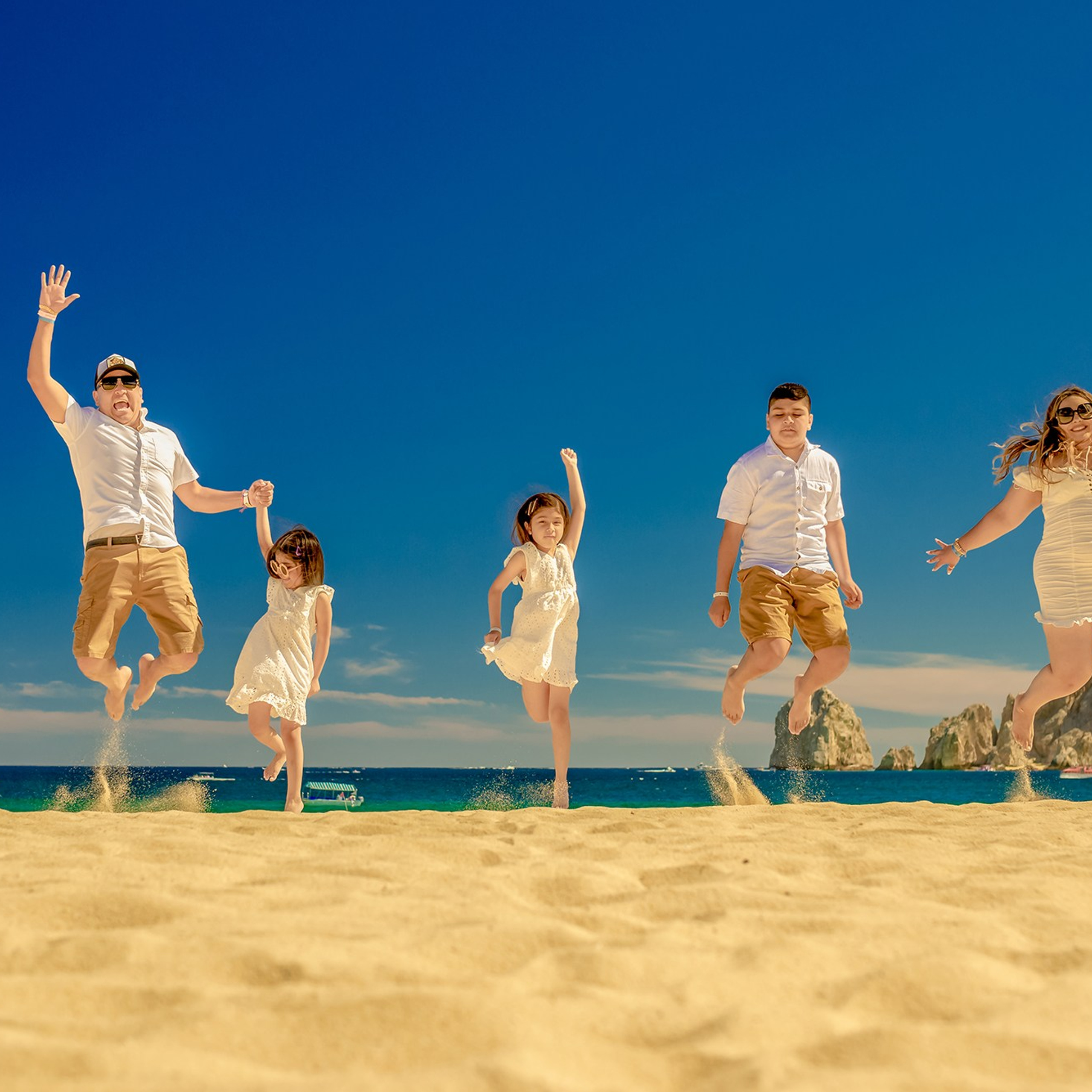 Family of five jumping on the beach in Los Cabos