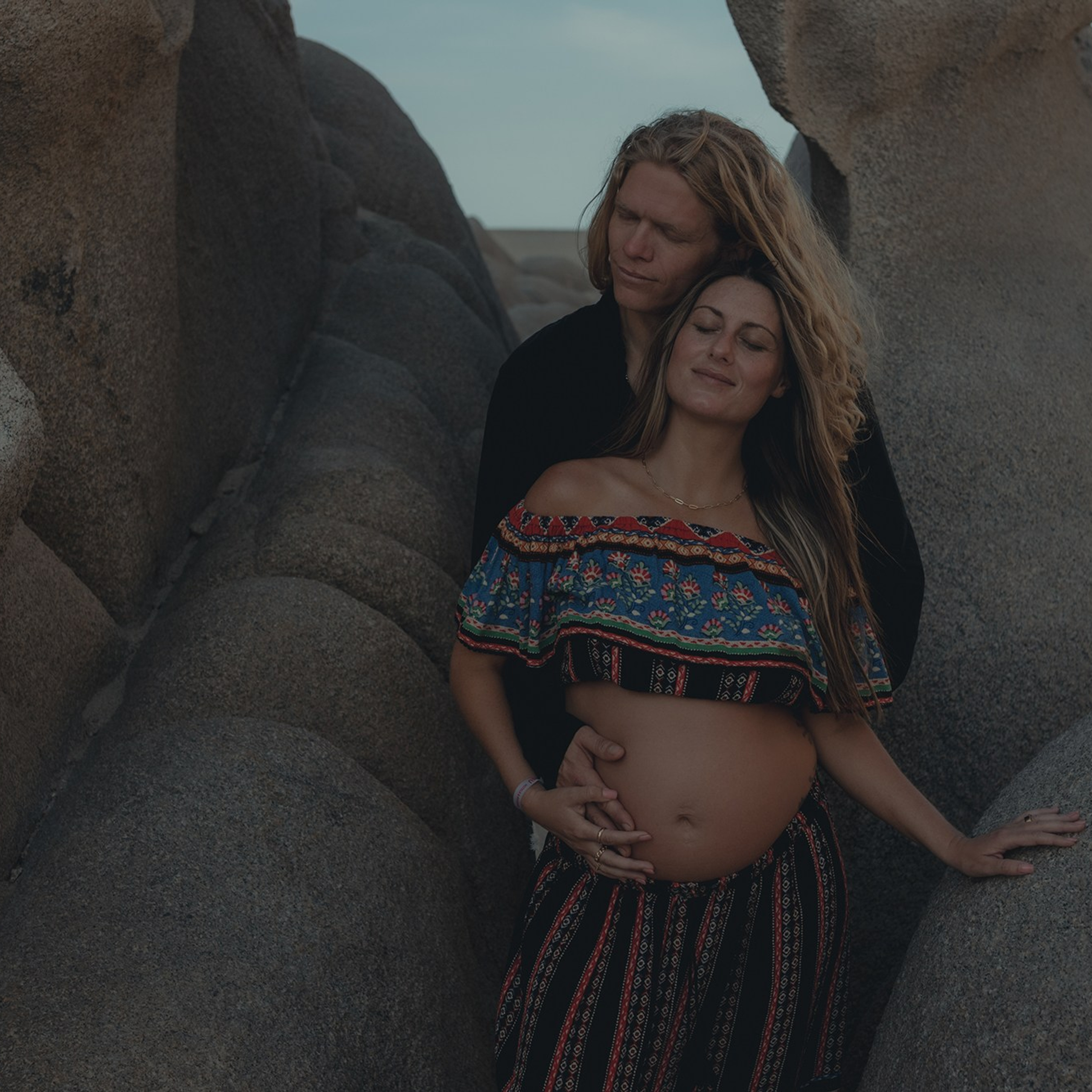 Cinematic maternity photoshoot in Playa del Amor, Los Cabos – pregnant mother and couple portraits with iconic rock formations, dramatic lighting and warm cinematic tones, destination maternity photographer in Baja California Sur