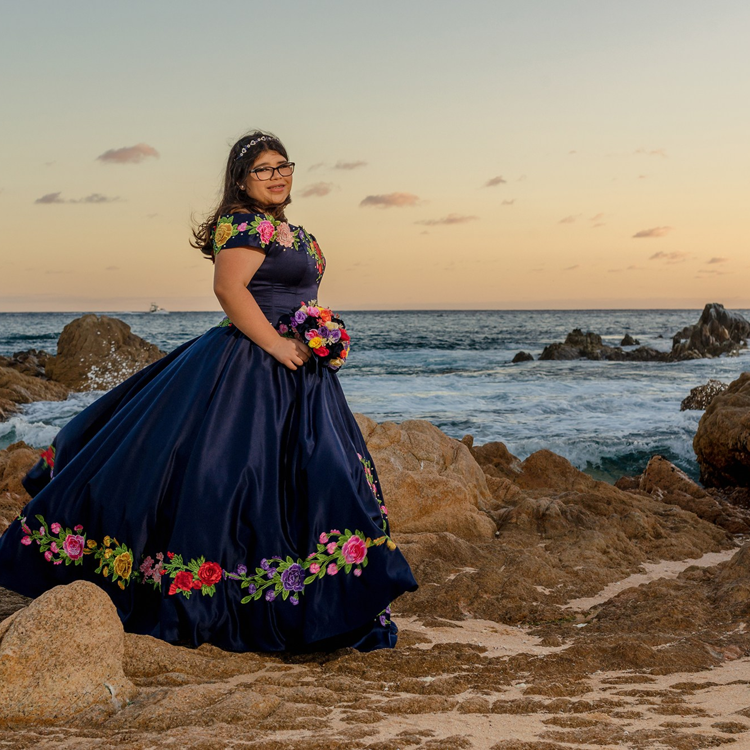 XV años photoshoot in Cabo San Lucas – quinceañera wearing a blue embroidered Mexican dress at Playa Las Viudas, captured at golden hour with the Pacific Ocean as backdrop