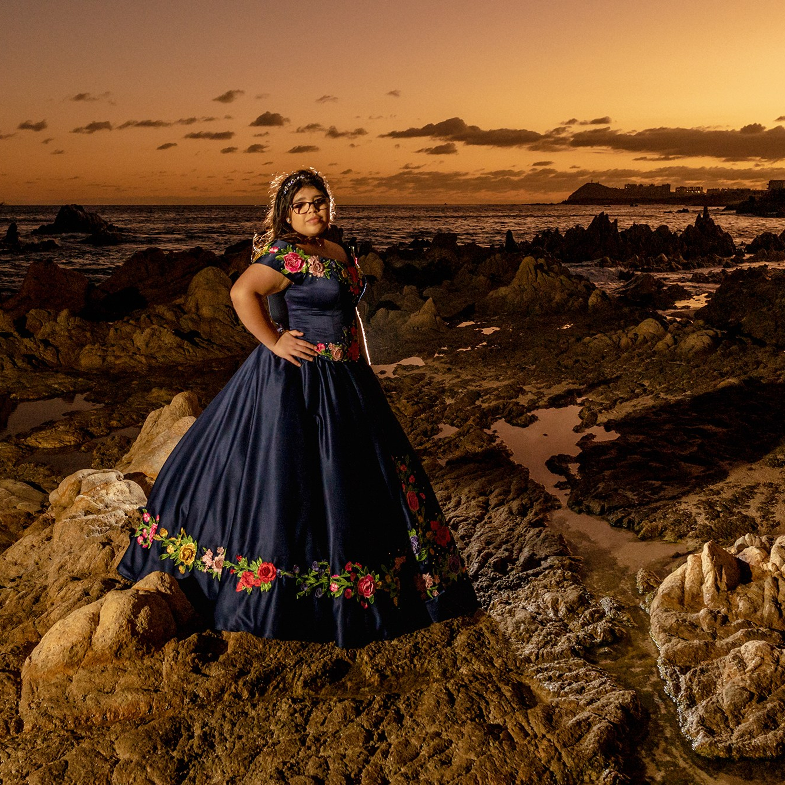 Cabo San Lucas XV años session – artistic portrait of quinceañera in embroidered Mexican blue gown with flowers, photographed at Playa Las Viudas during sunset by destination photographer