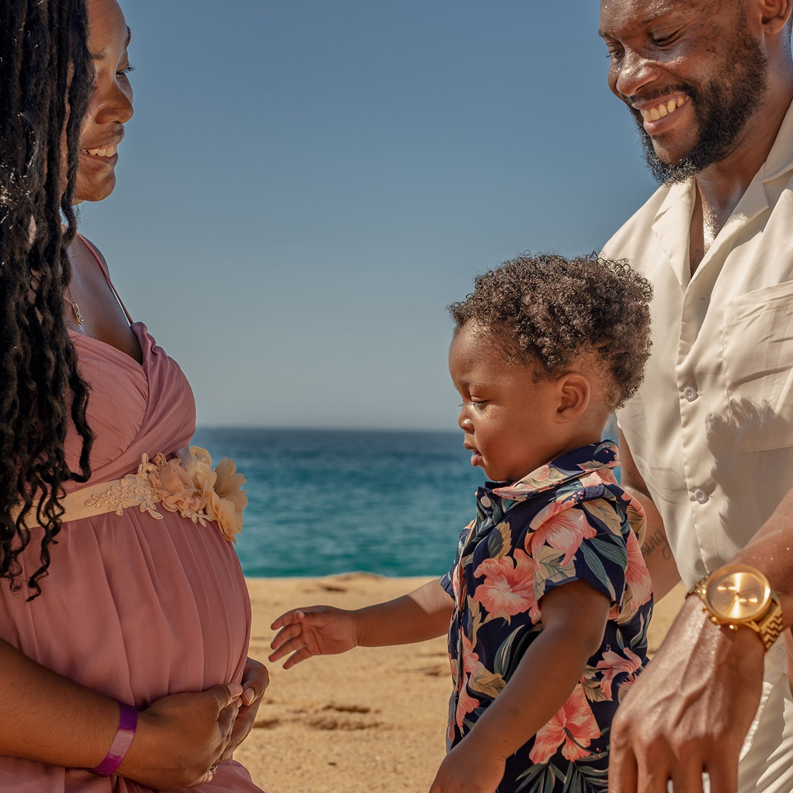 Family maternity photoshoot in Los Cabos – expecting couple with their first child embracing the mother’s baby bump, beach and ocean backdrop, destination family photographer in Cabo San Lucas