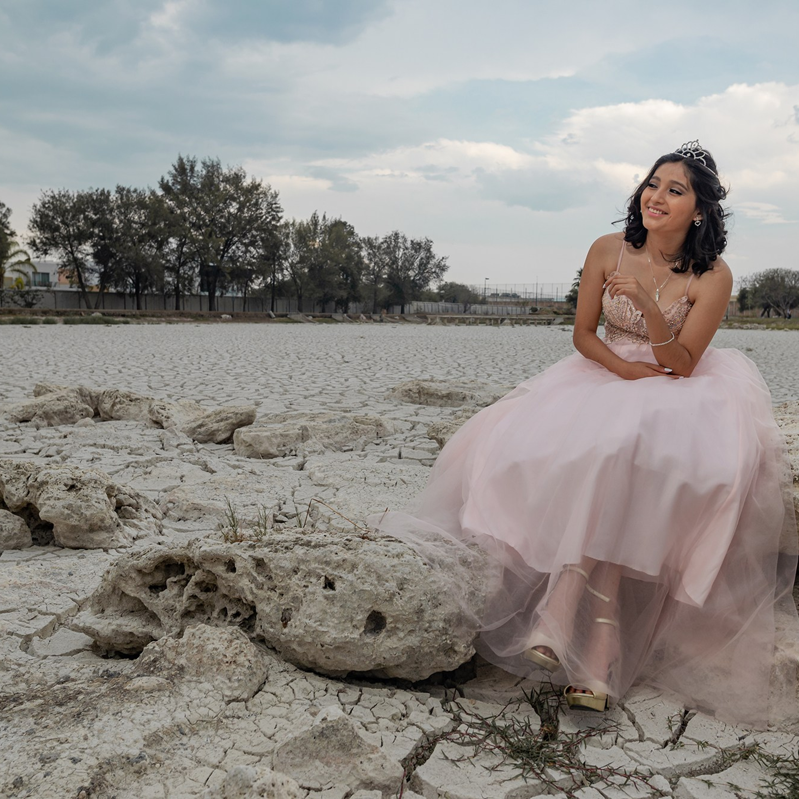 Creative fashion-inspired photoshoot in Baja California Sur – Michelle wearing a pink quinceañera-style dress in a desert landscape with cracked ground, artistic photography in Los Cabos