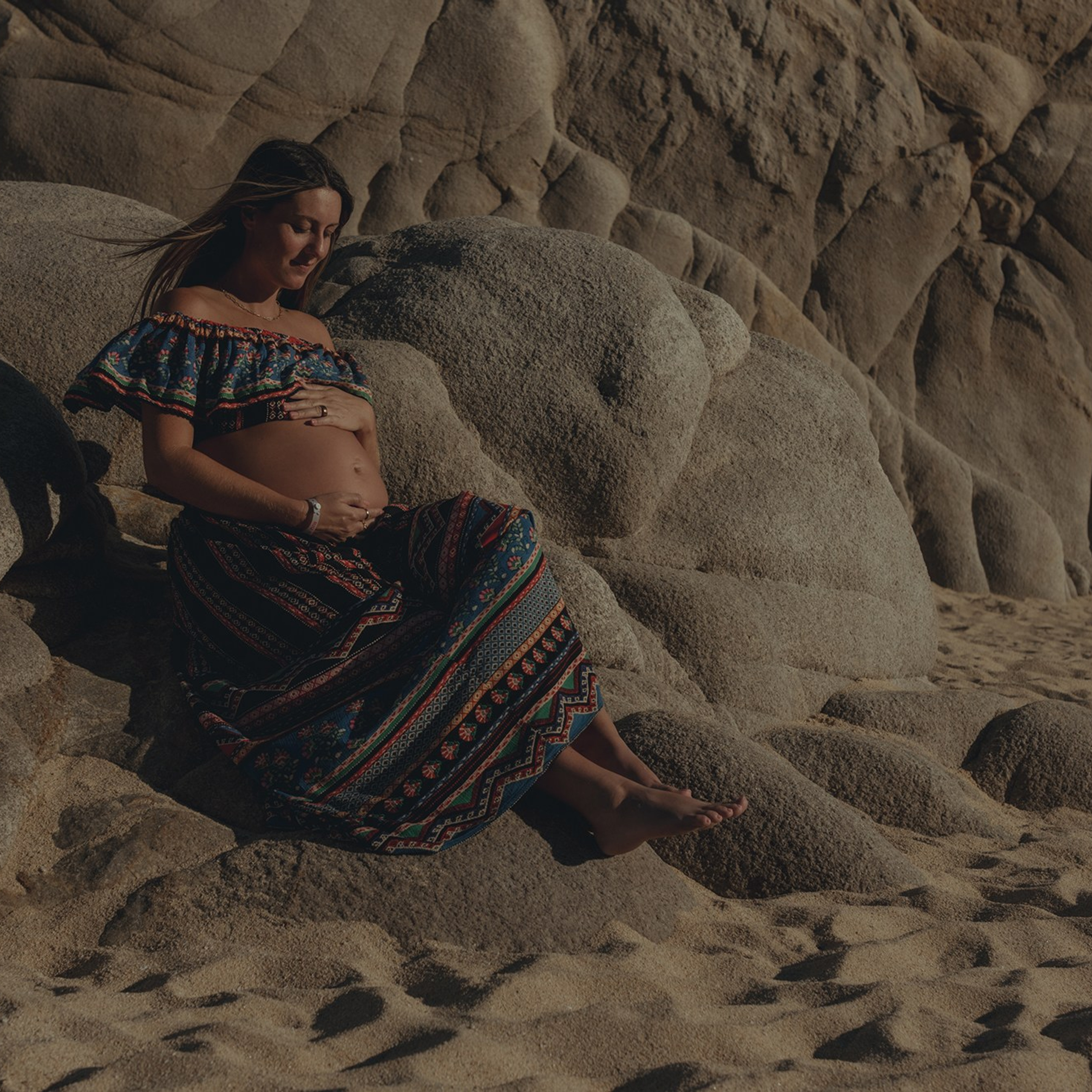Los Cabos maternity photography – expecting couple and mother-to-be captured at Playa del Amor with cinematic style, warm color grading, ocean and rocky cliffs in the background