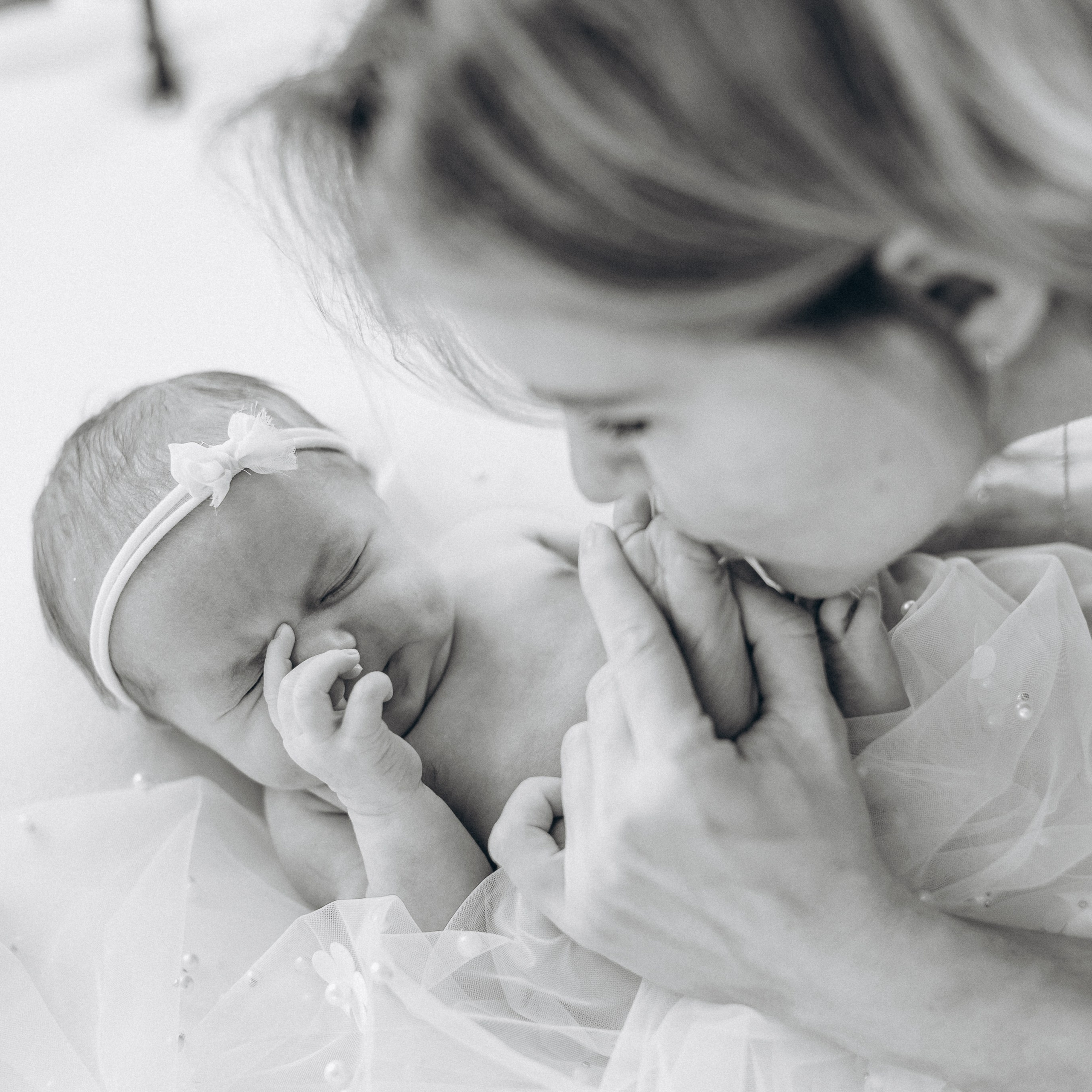 Mutter küsst Füsschen ihres süßen neugeborenen Mädchens.