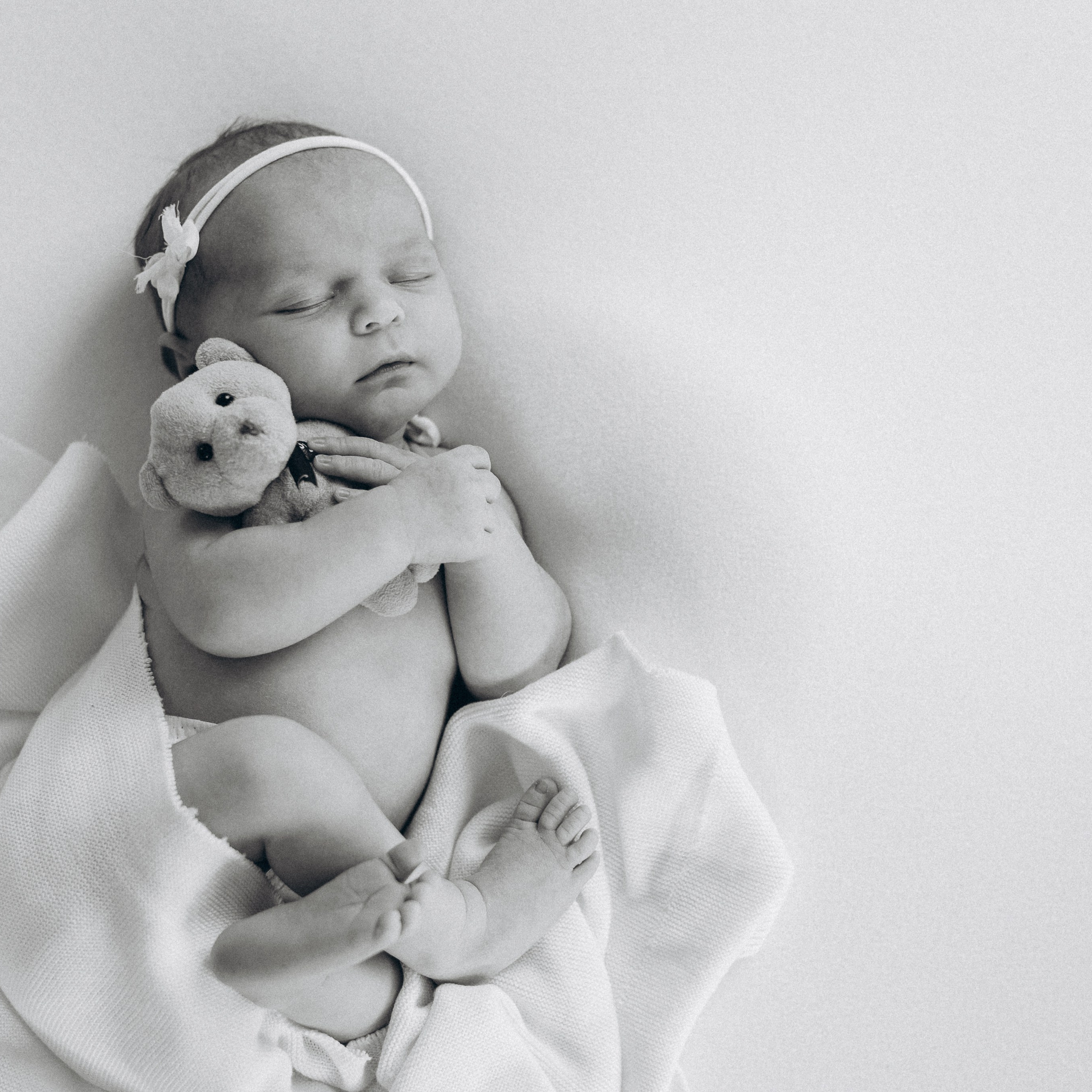 Ein neugeborenes Mädchen mit dem Teddy im Arm bei einem Newbornshooting in Hörstel.