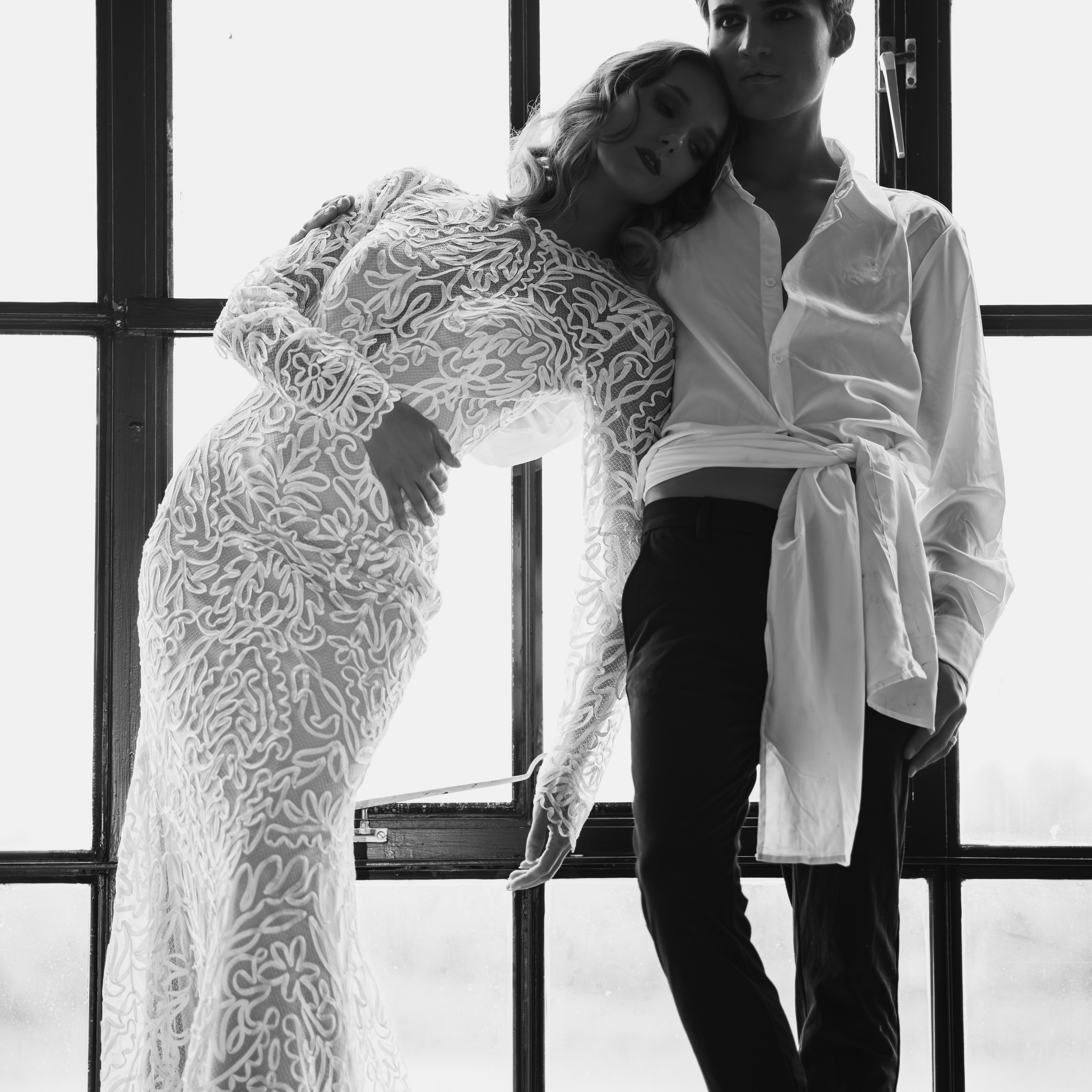 toere trouwfoto van bruid en bruidegom tegen raampartij in een industrieel pand - Kapture Fotografie