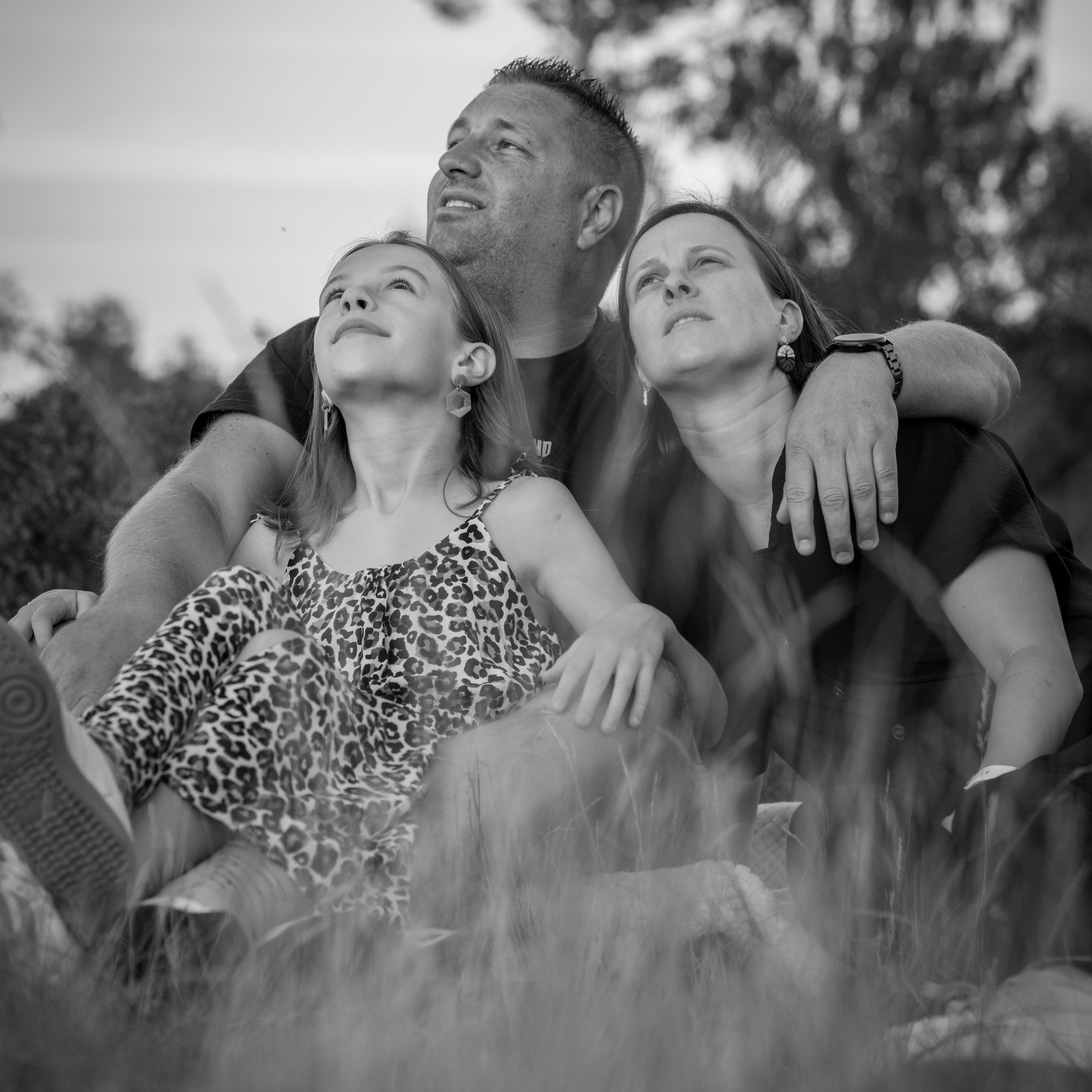 Zwart-wit familiefoto van gezin zittend in het gras tijdens spontane buitenfotoshoot door Kapture Fotografie