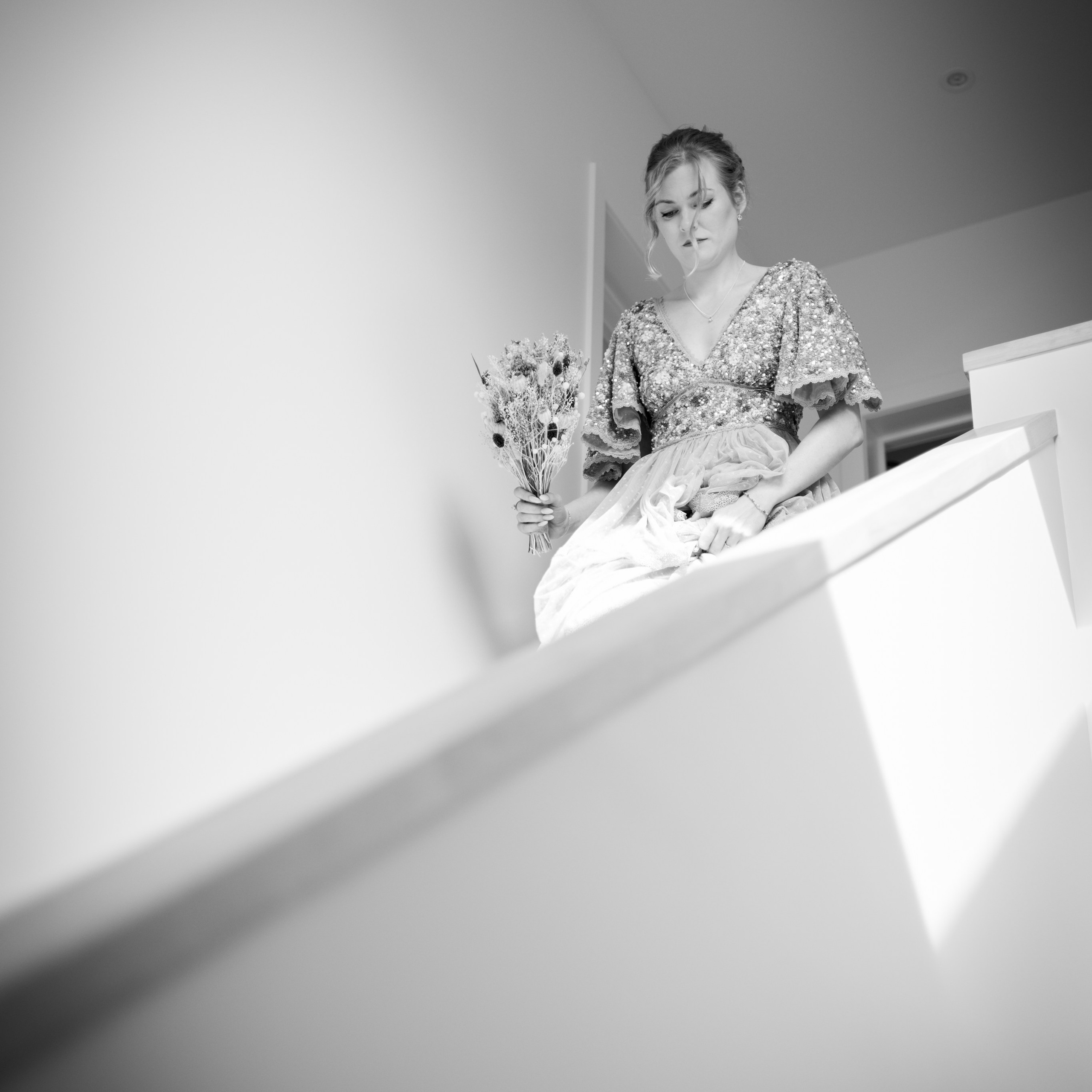 Zwart-wit foto van bruid die de trap afkomt tijdens huwelijksvoorbereiding vastgelegd door Kapture Fotografie