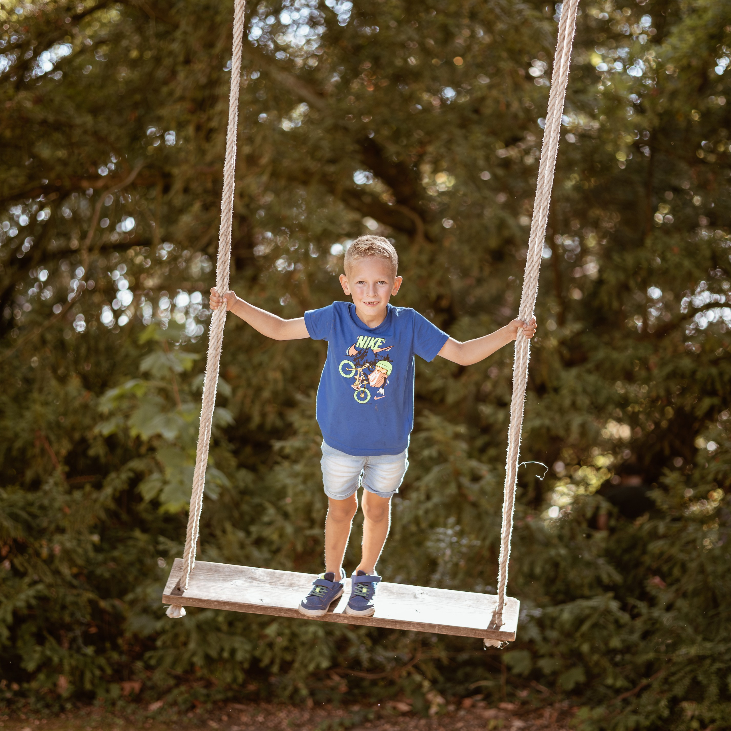 Kind schommelt in de neergaande zon tijdens warme en speelse buitenfotoshoot door Kapture Fotografie