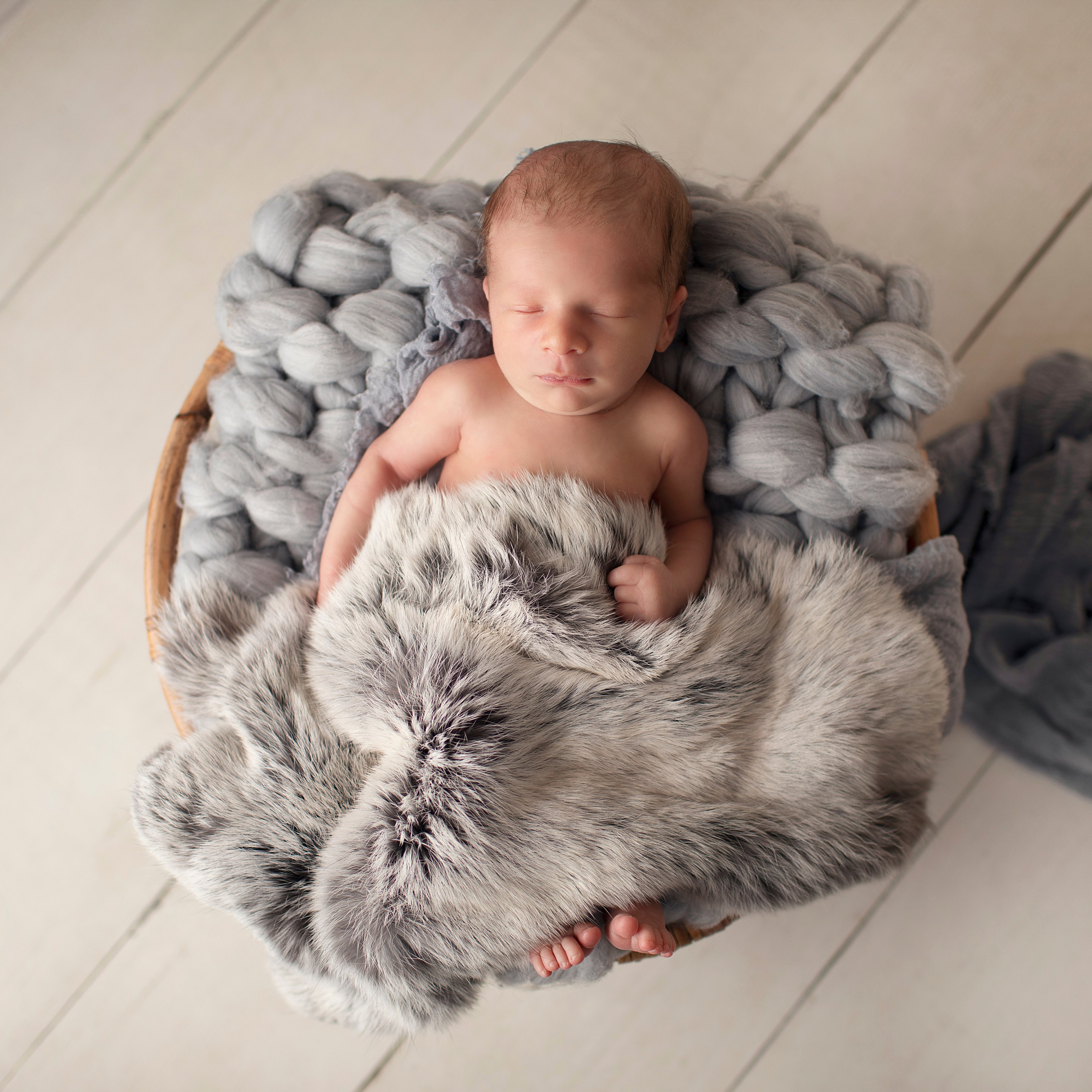 "Söt nyfödd baby som ligger i en mjuk filt med ett lugnt uttryck. Bilden är utmärkt för webbplatser som fokuserar på babyfotografi och nyfödda bilder."