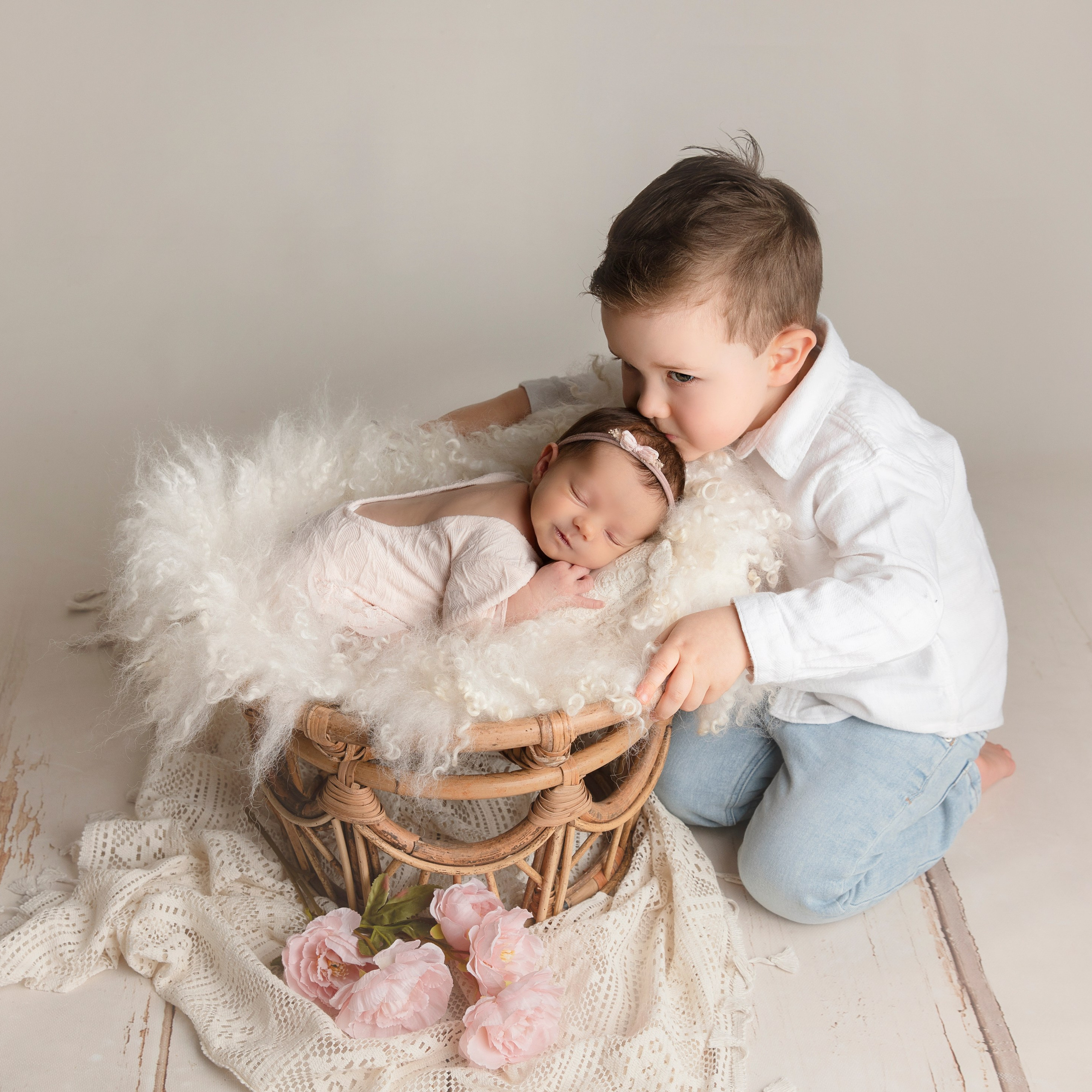 "Nyfödd bebis som ligger i knäet på sitt äldre syskon. Bilden visar den speciella relationen och ömheten mellan dem och passar utmärkt för att framhäva familjeband i nyfödda fotograferingar."