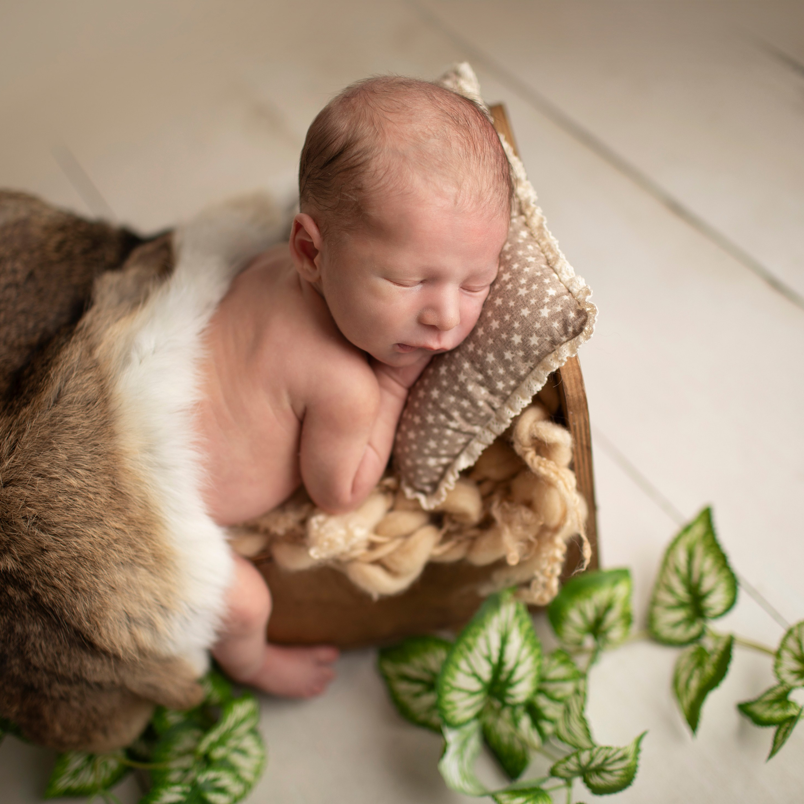 "Söt nyfödd baby som ligger i en mjuk filt med ett lugnt uttryck. Bilden är utmärkt för webbplatser som fokuserar på babyfotografi och nyfödda bilder."