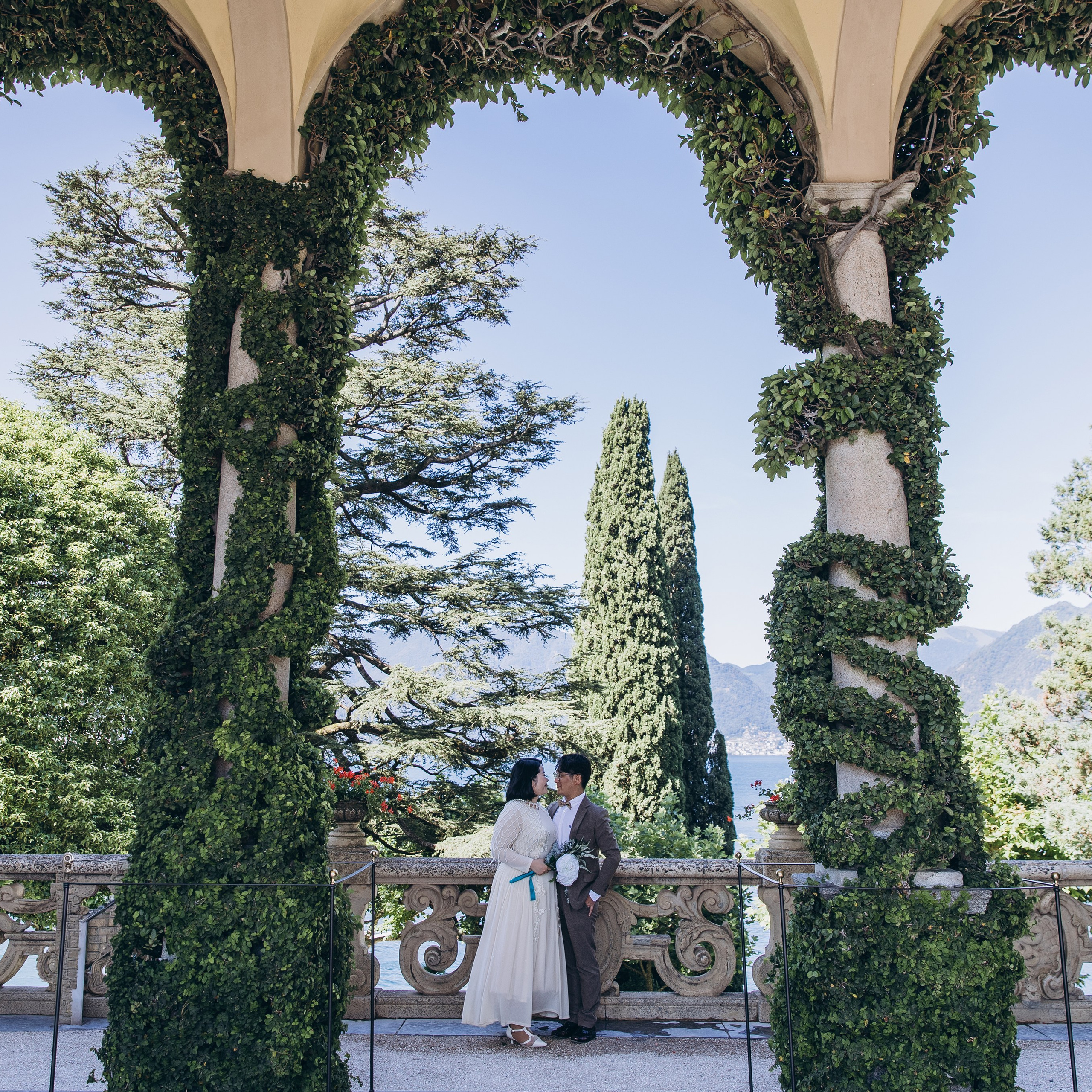 Lake Como wedding photos featuring a couple beneath ivy-covered stone arches in a historic villa garden