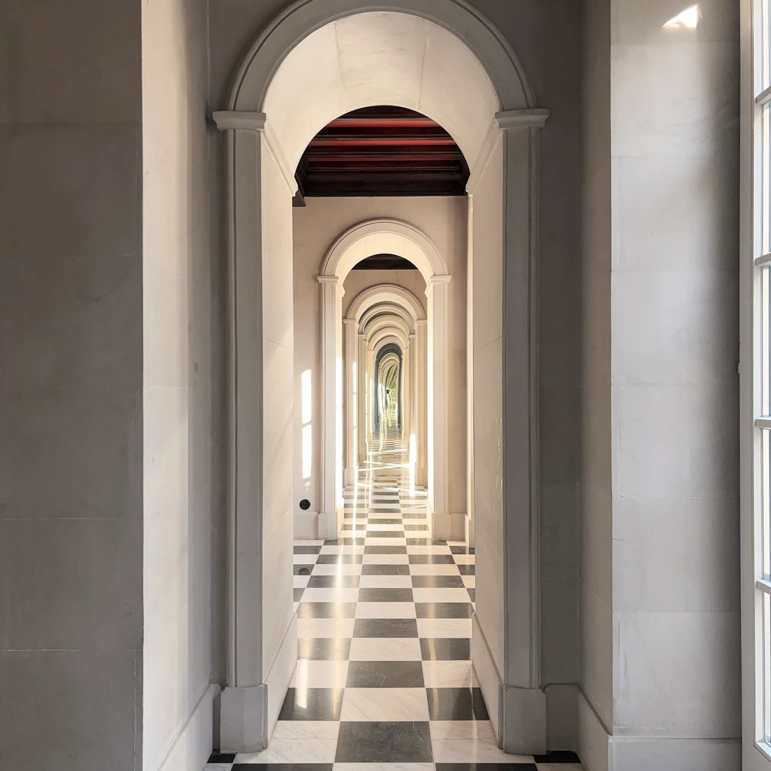 Długi korytarz w stylu neoklasycznym – imponująca architektura z arkadami i geometrycznym wzorem posadzki