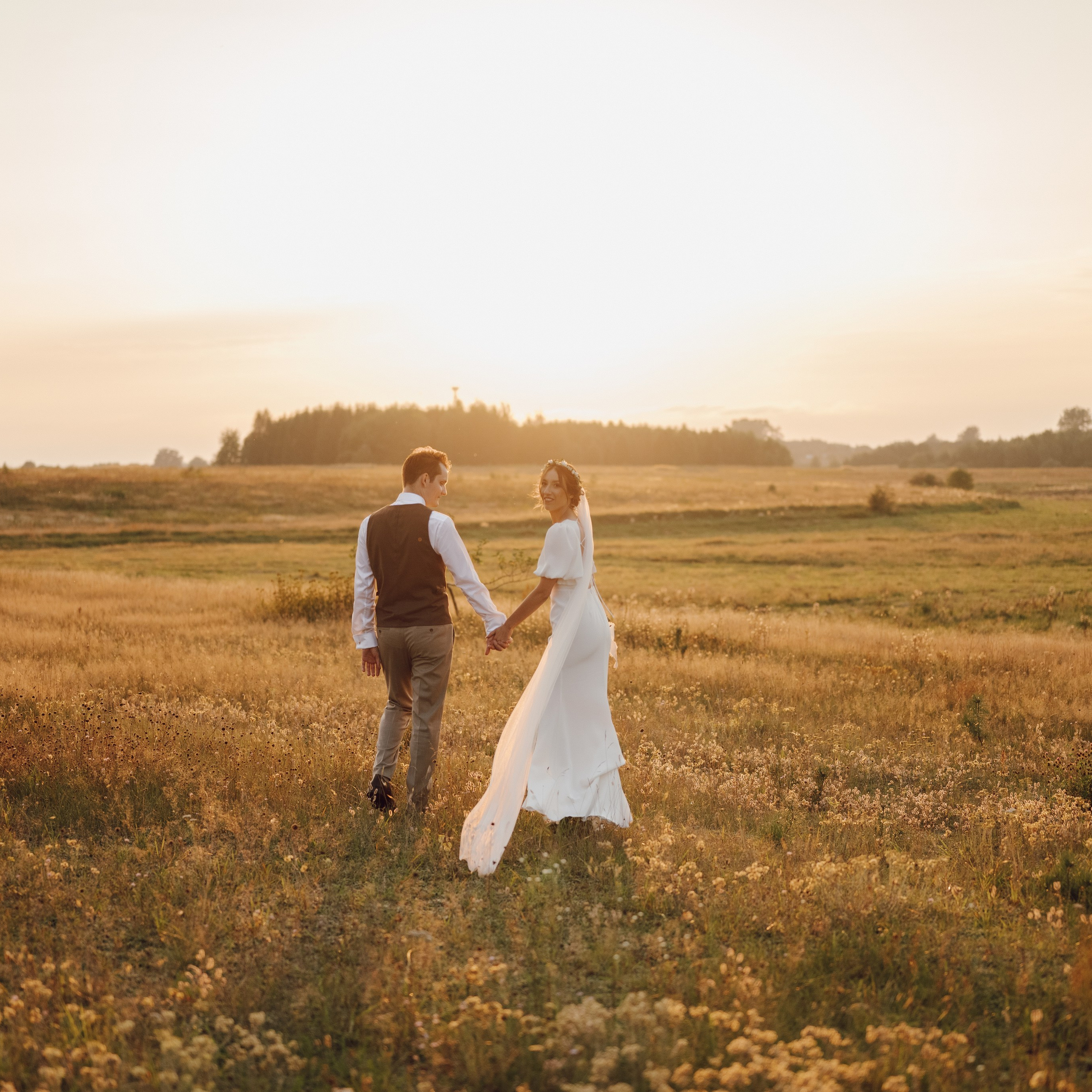 Spacer pary młodej po łące – rustykalna sesja ślubna, fotograf ślubny Poznań i okolice.