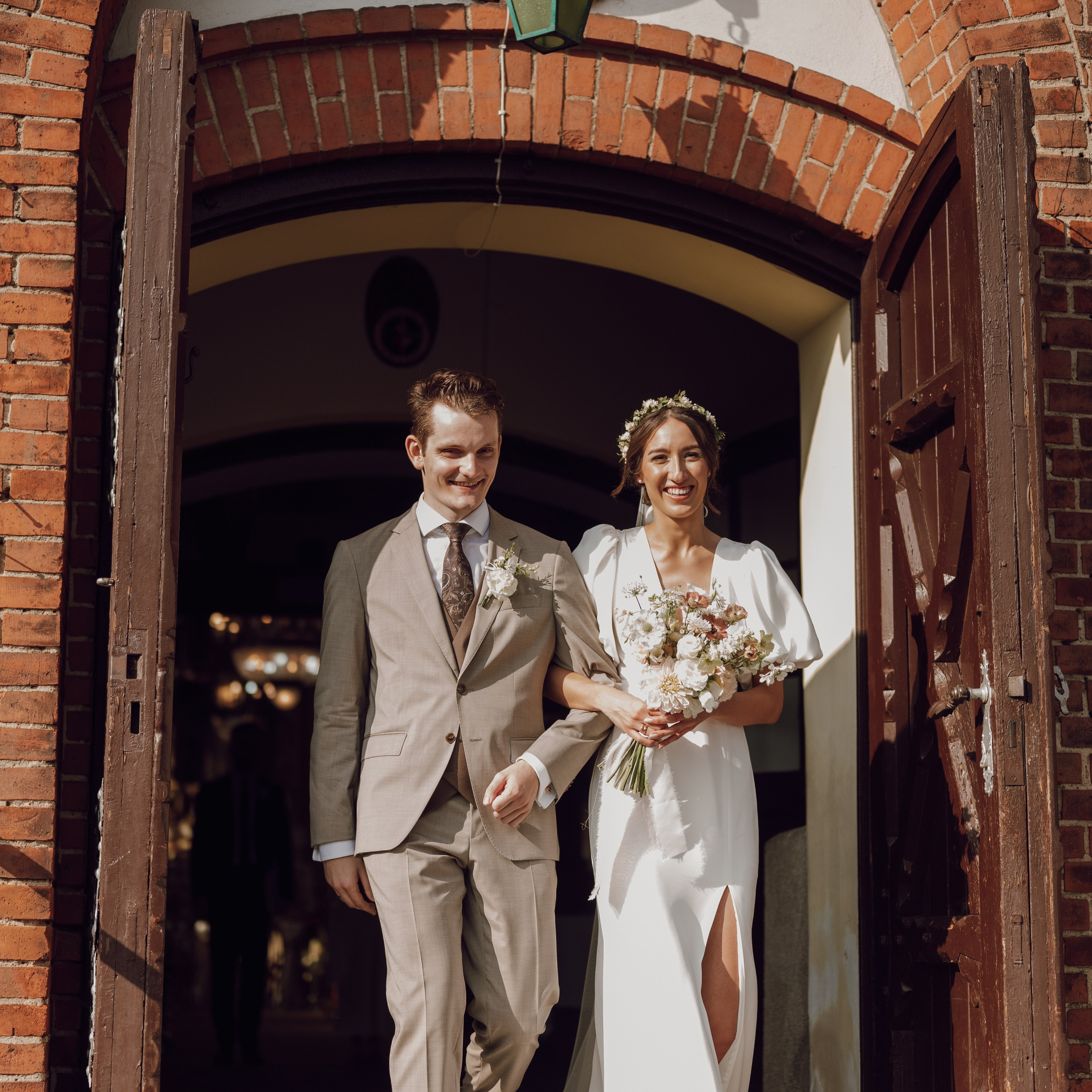 Para młoda wychodząca z kościoła – radosny moment po ceremonii, ślub w Poznaniu.