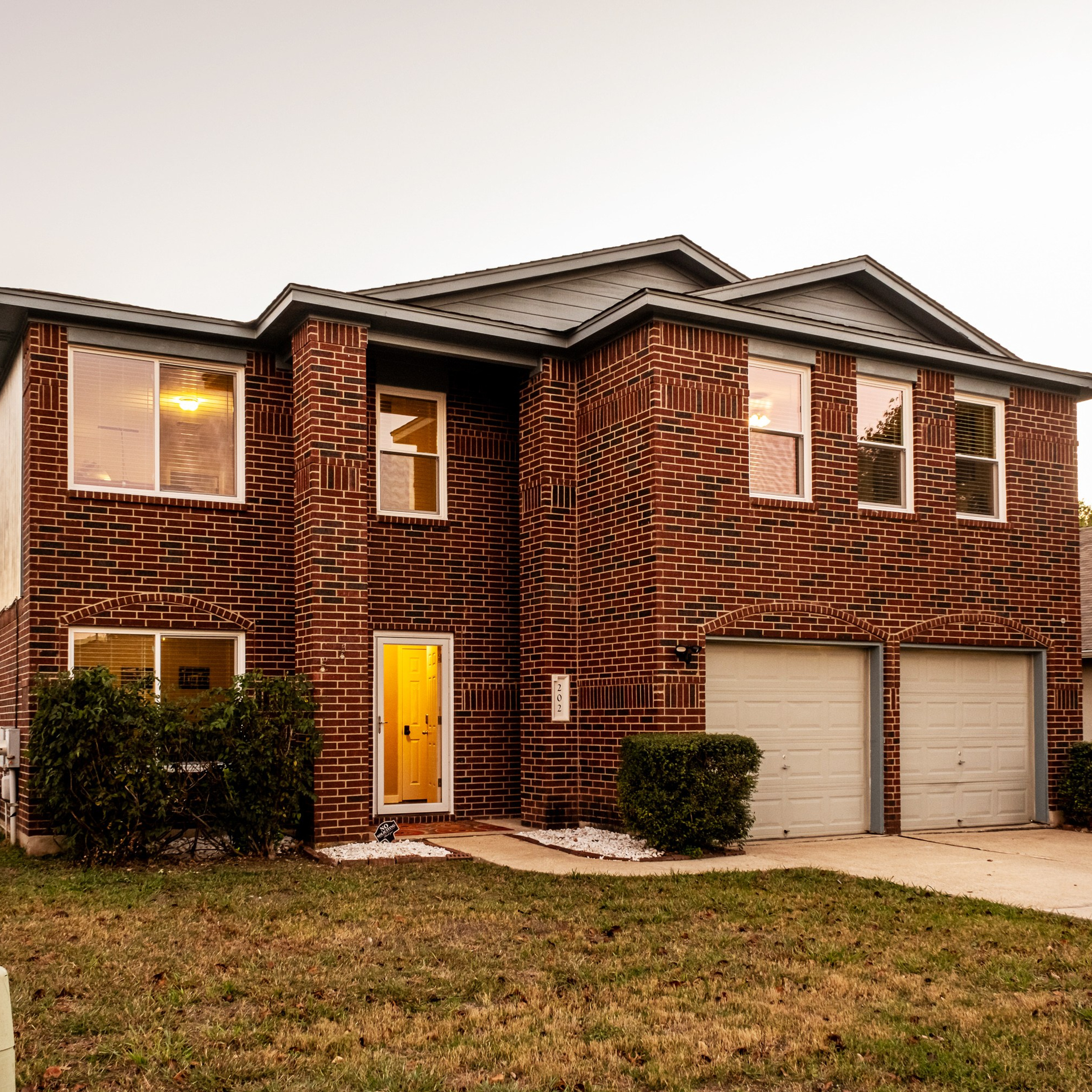 Luxury home exterior twilight photography with pool and warm interior lights Austin TX