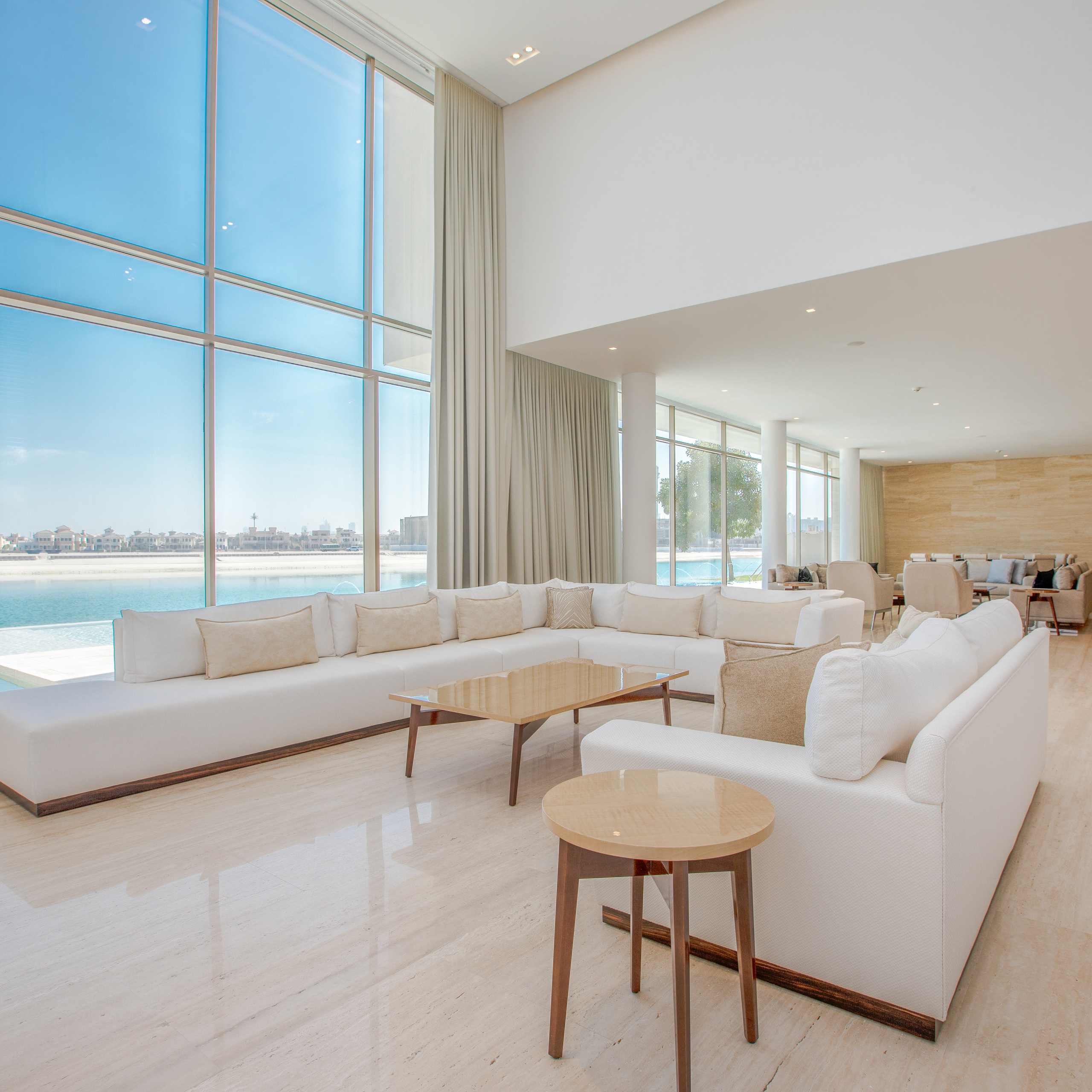 Spacious modern living room with large floor-to-ceiling windows offering a scenic view of the waterfront