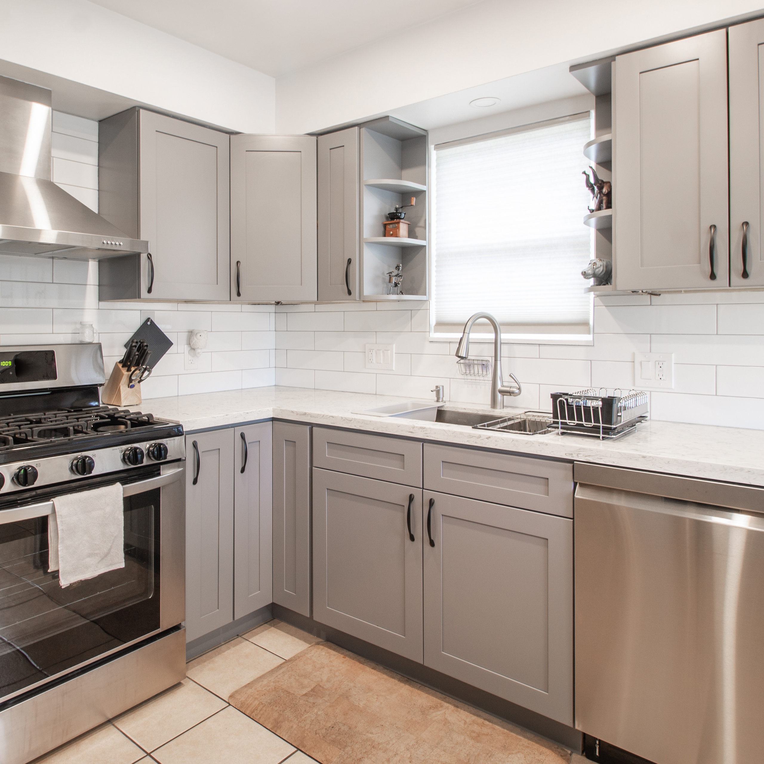 Bright kitchen with gray shaker cabinets, stainless steel range hood, and a white countertop