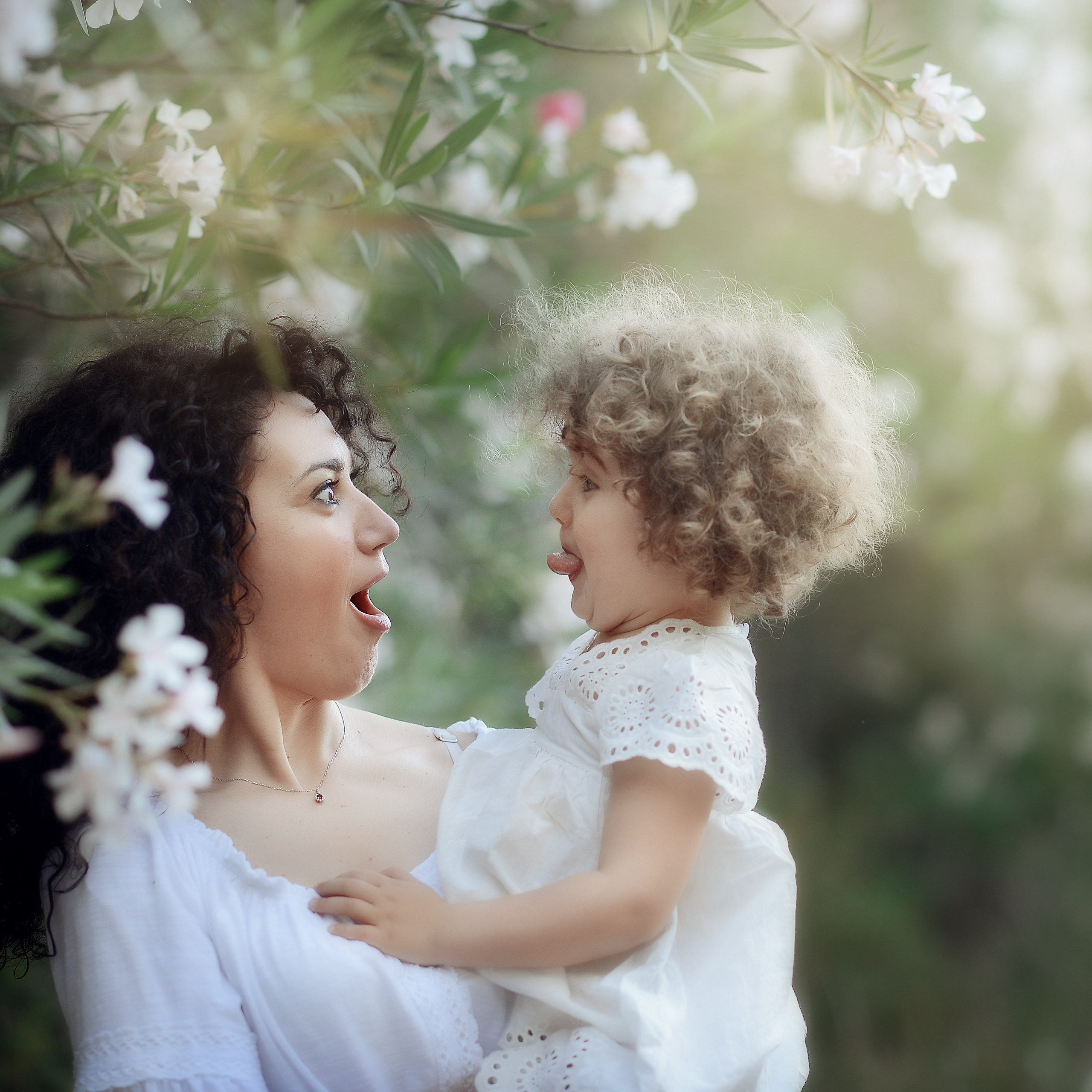 Mother and daughter making funny faces among blooming oleanders in Puglia.