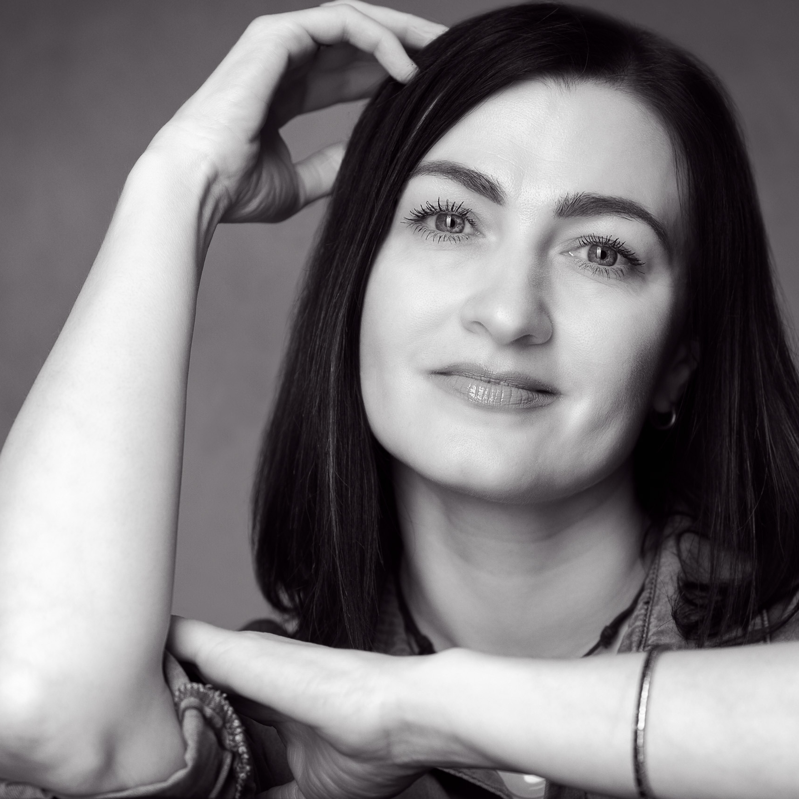 Ein großer Schwarz-Weiß-Porträt einer schönen Brünetten am Tisch mit sichtbar gekreuzten Armen.