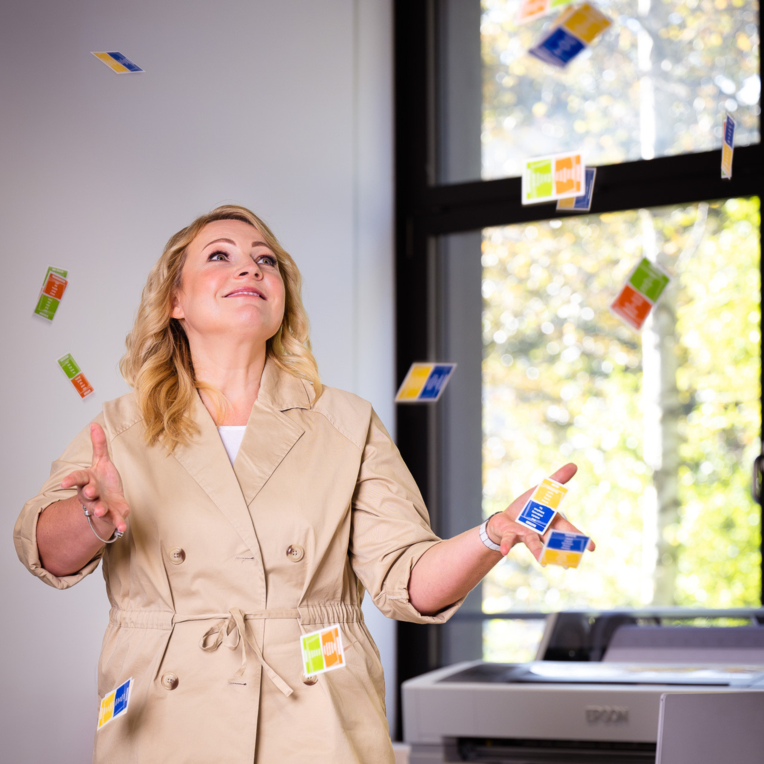 Eine Lehrerin in einem beigen Anzug jongliert geschickt mit Spielkarten in der Luft.