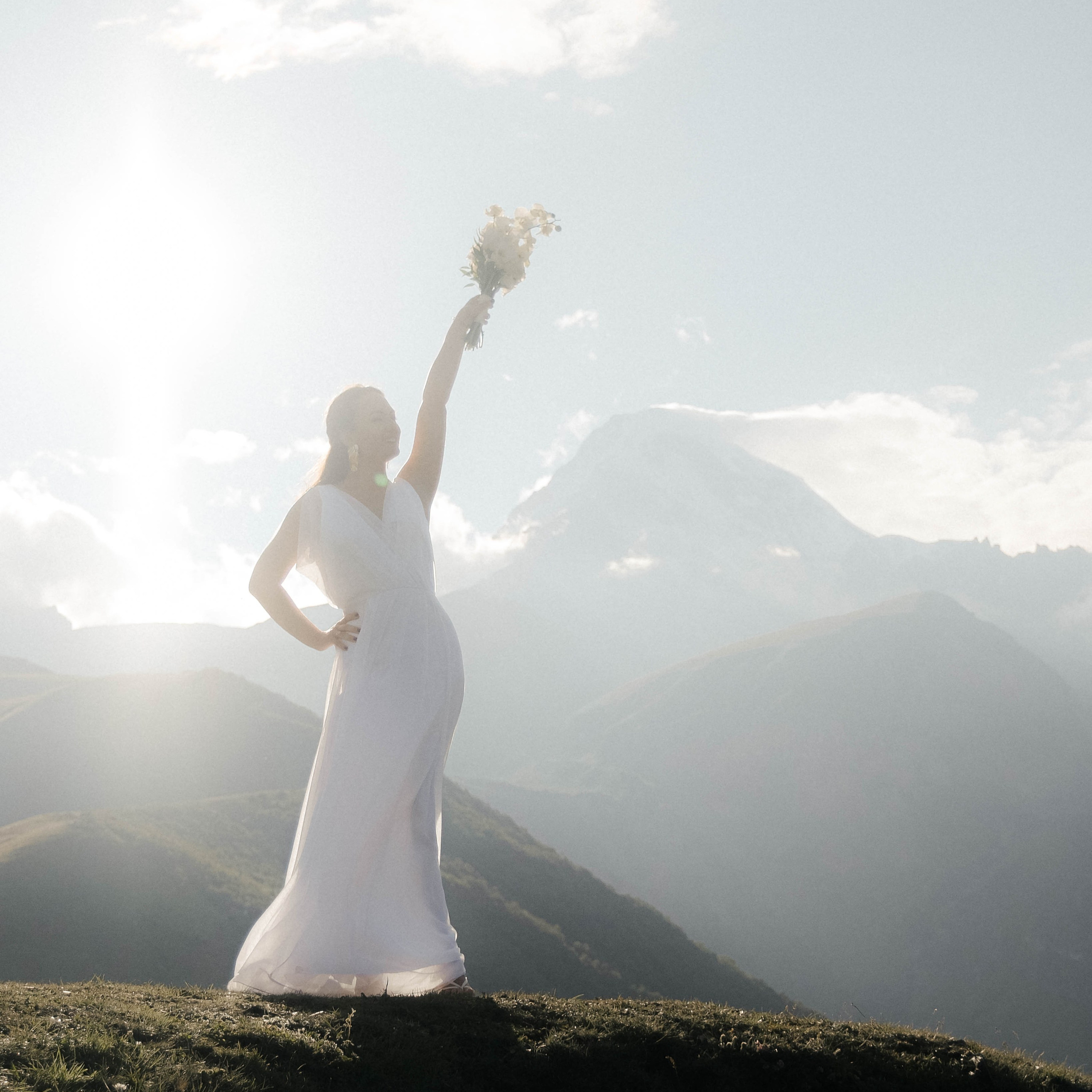 Bride's dress flowing in wind, mountain Kazbegi view