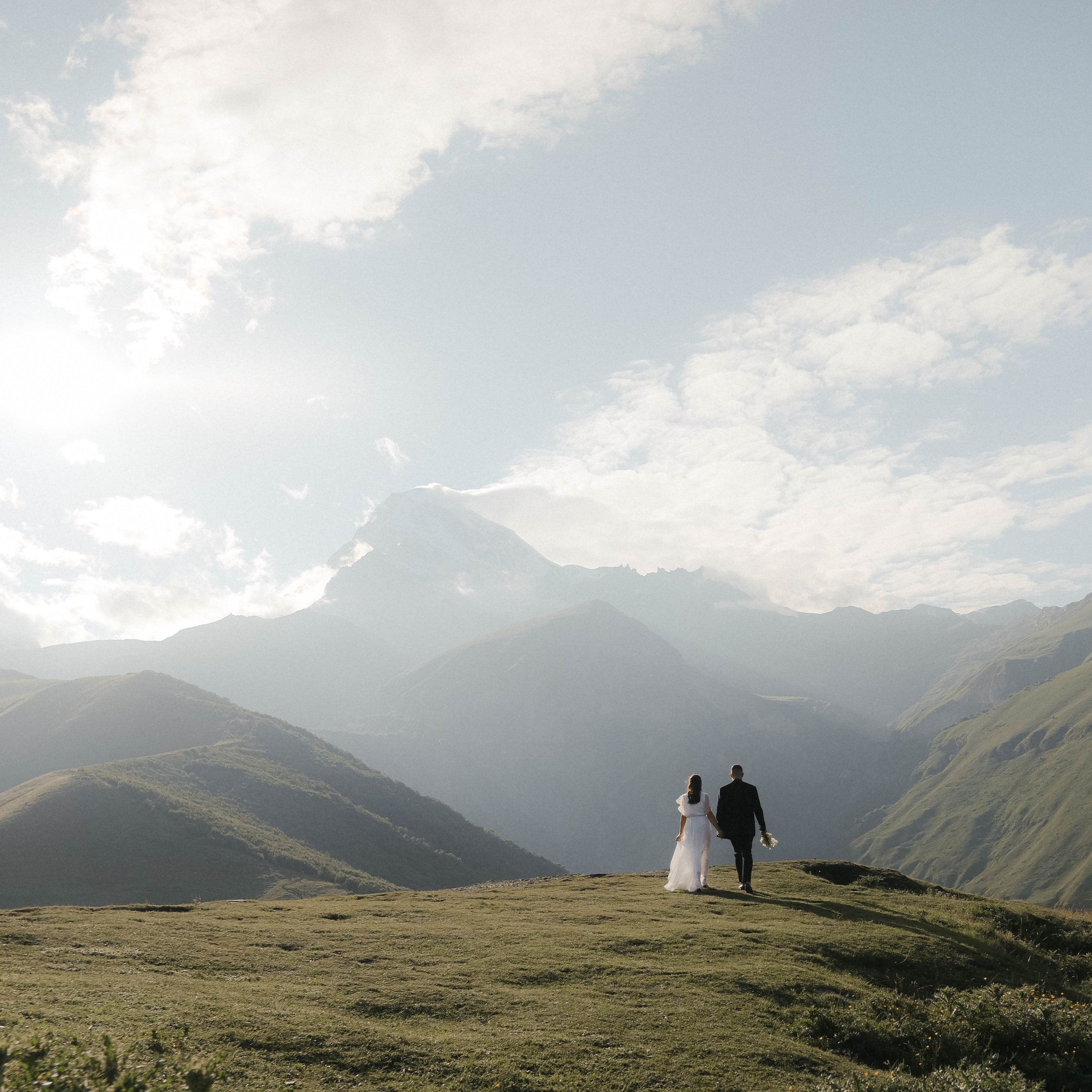 Couple holding hands, golden hour light, Georgian mountains