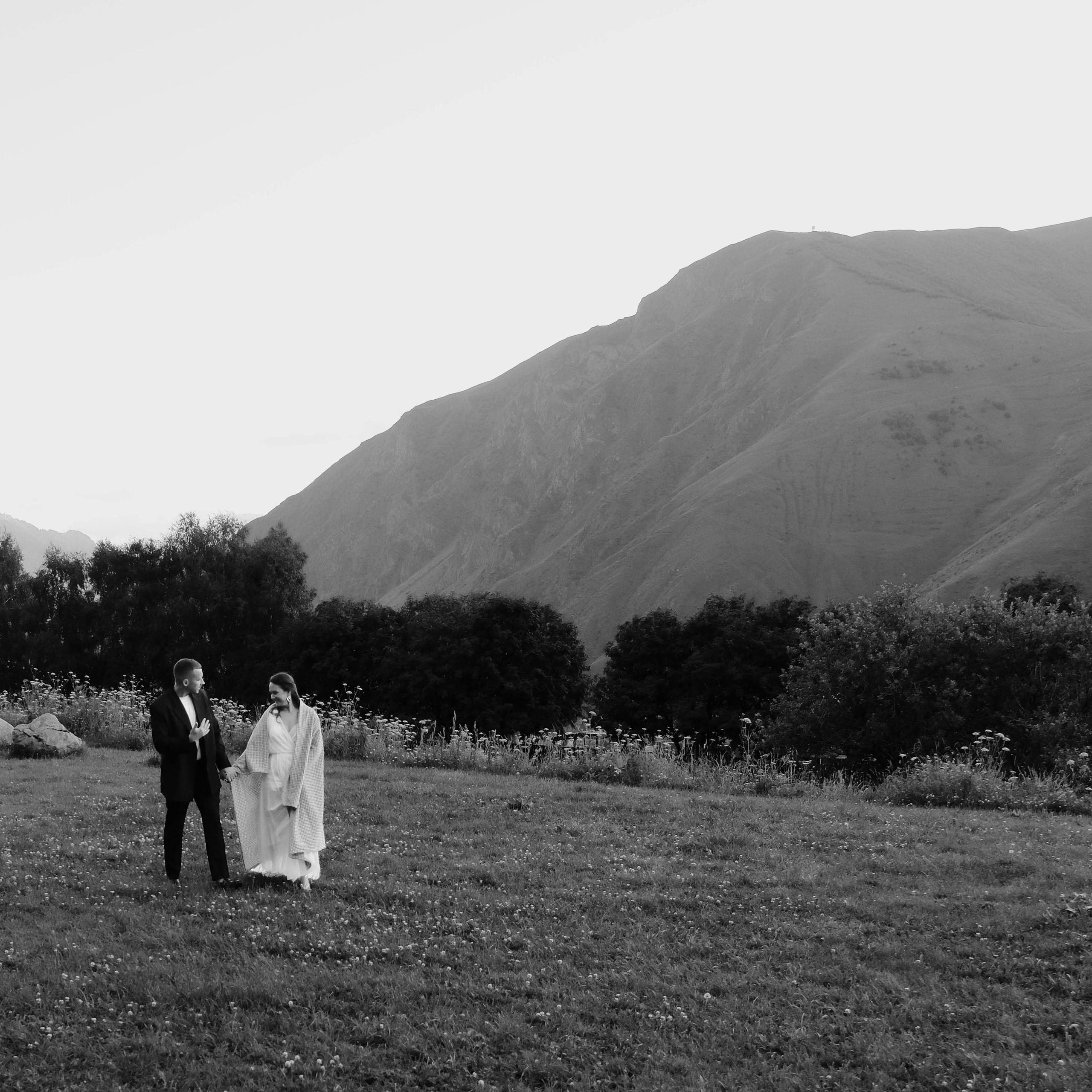 Bride and groom walking through Kazbegi mountain landscape