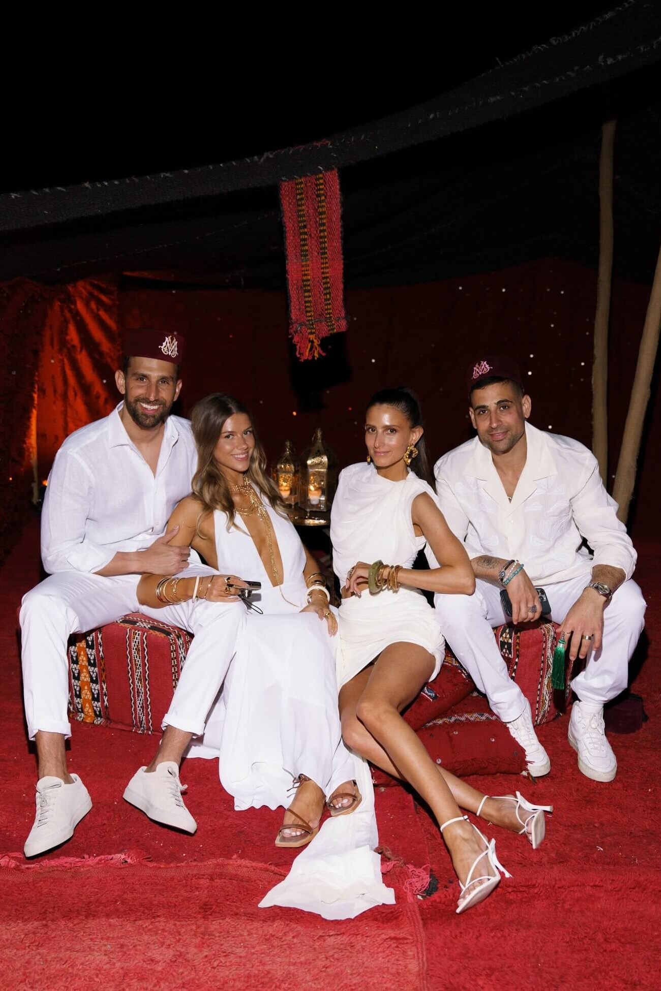 Bride and groom sitting with friends during a stylish evening wedding celebration in Marrakech