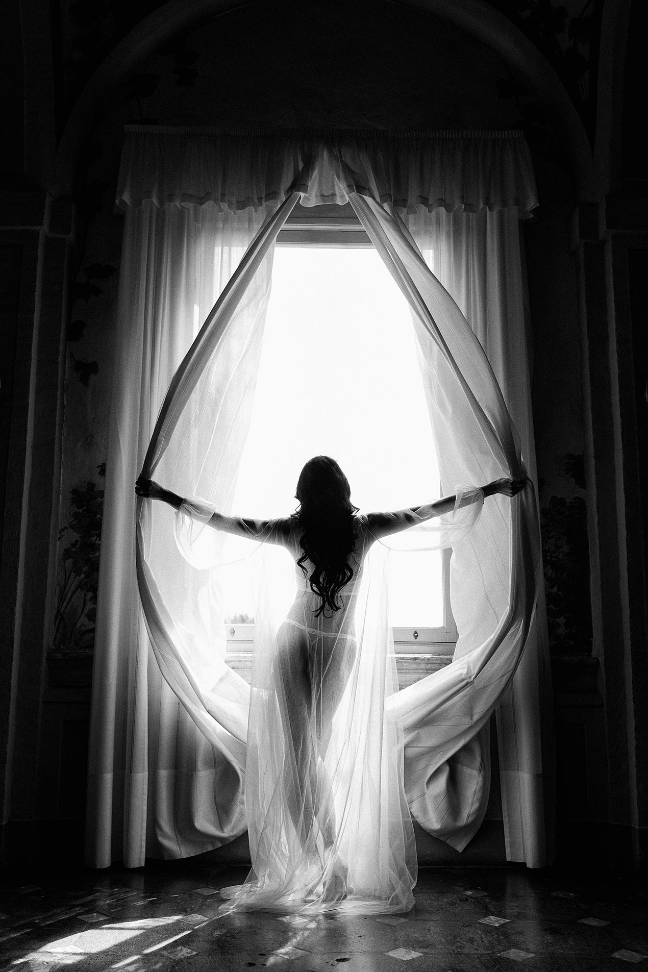 Mireasă lângă fereastră într-o ședință foto boudoir cu lumină naturală