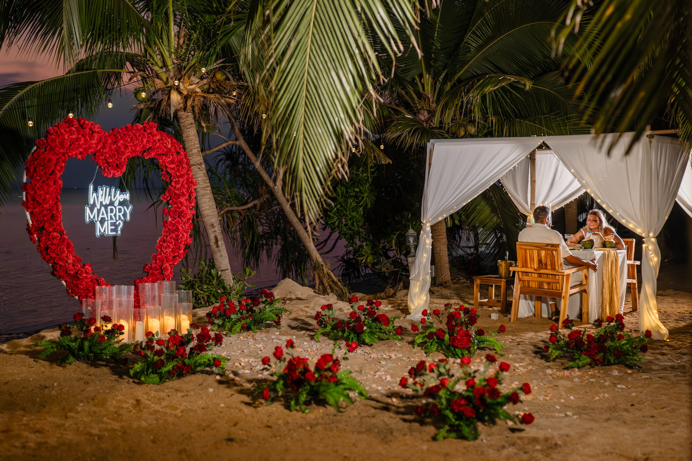 Elegant “Marry Me” beach proposal setup in Koh Samui with rose petals and tropical decor.