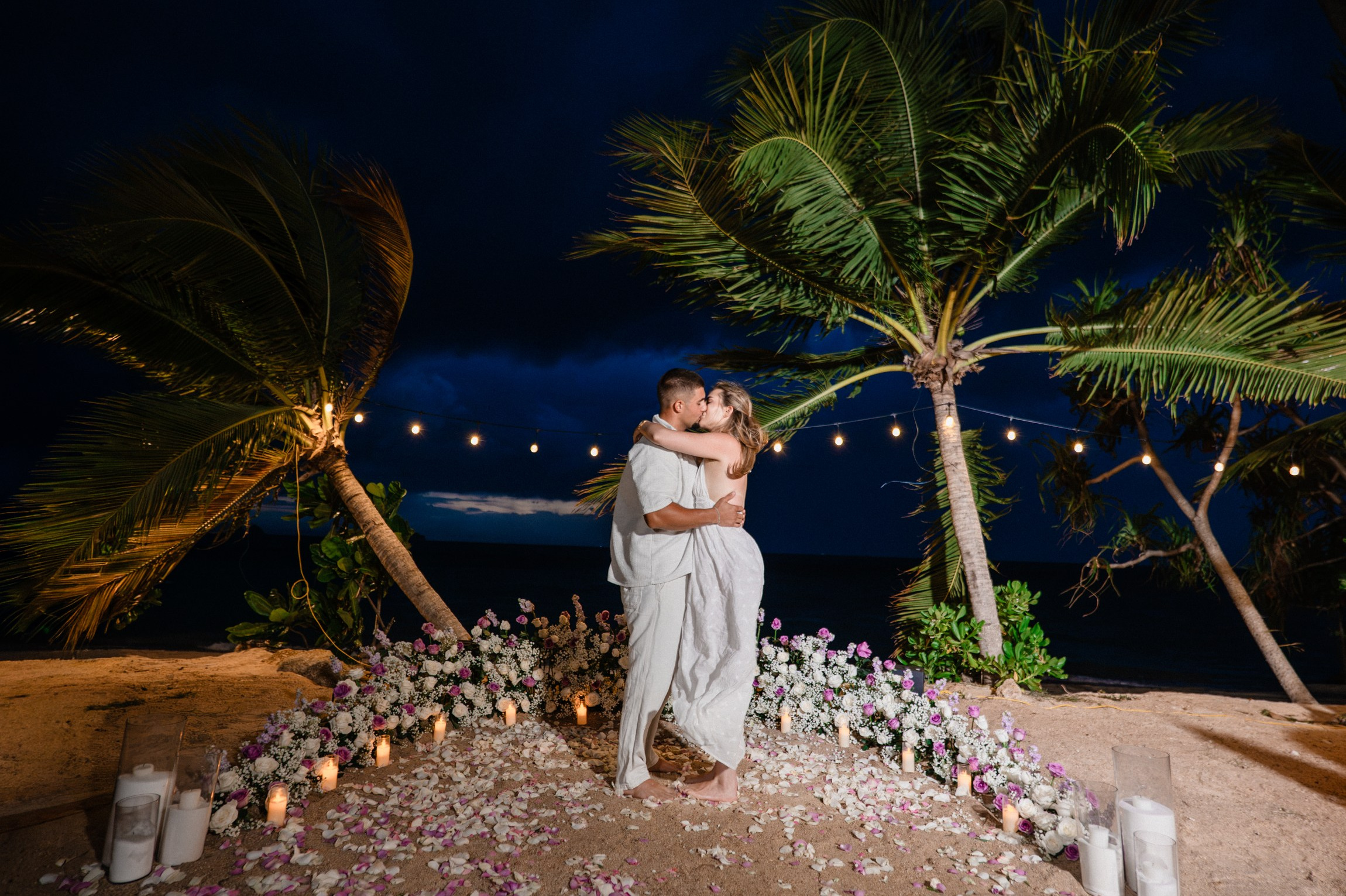 Romantic beach proposal setup in Koh Samui, Thailand with candles, flowers and ocean sunset view.