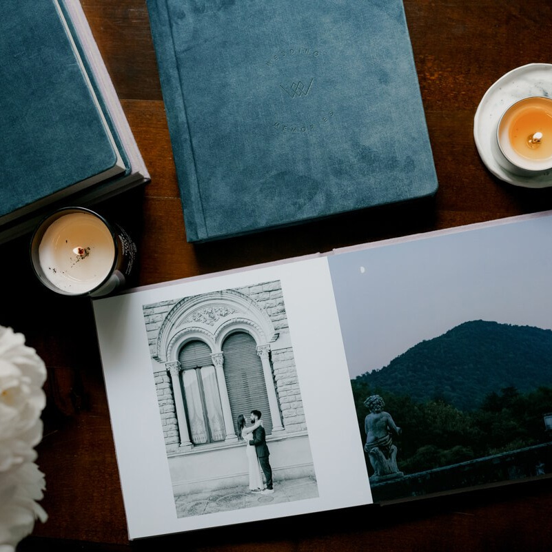 Open wedding album displaying ceremony portraits beside candlelight