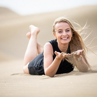 Desert Dunas Maspalomas Girl in Sand - A woman laying on a sand dune with her hands in the sand.