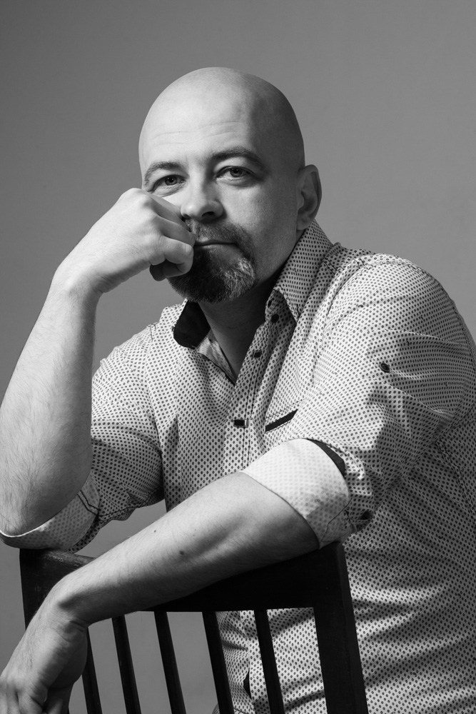 Чорно-білий студійний портрет чоловіка з піднесеною рукою до обличчя