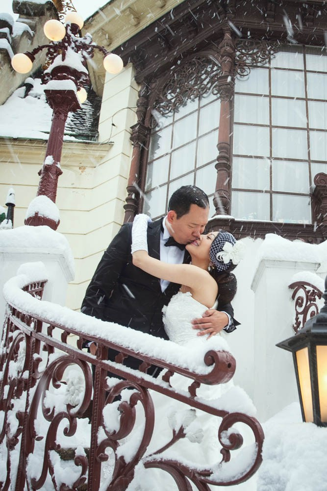 Helen and CY share a kiss on the snow-covered steps of the Hanavský pavilon during their pre-wedding session.