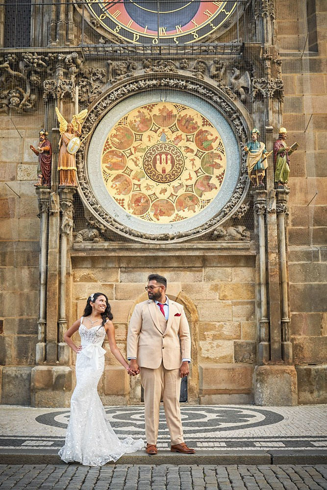 Bride in lace gown lifted below the astronomical clock calendar dial in Old Town Square