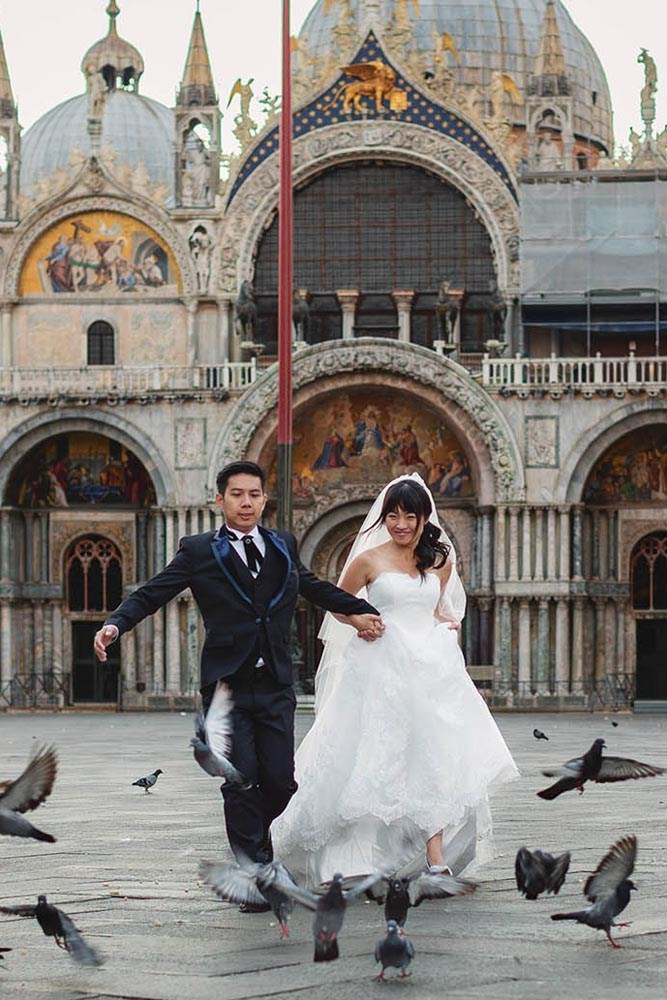 Candid engagement session — couple share a playful moment beneath the Astronomical Clock in Old Town Square, Prague — Kurt Vinion Photography