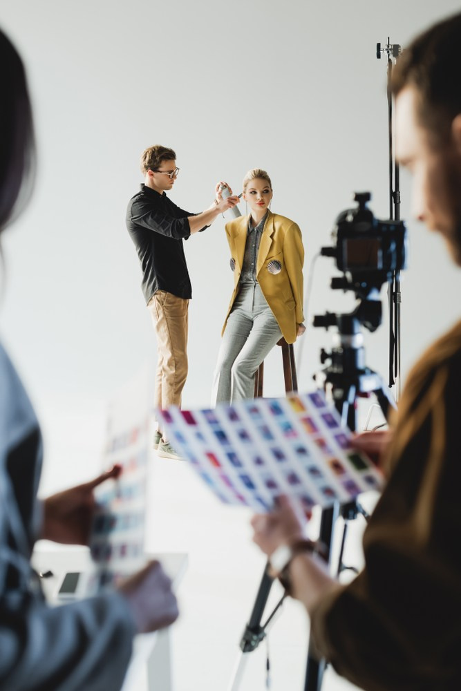 Team working on a fashion photoshoot, with a stylist adjusting the model's outfit while others observe