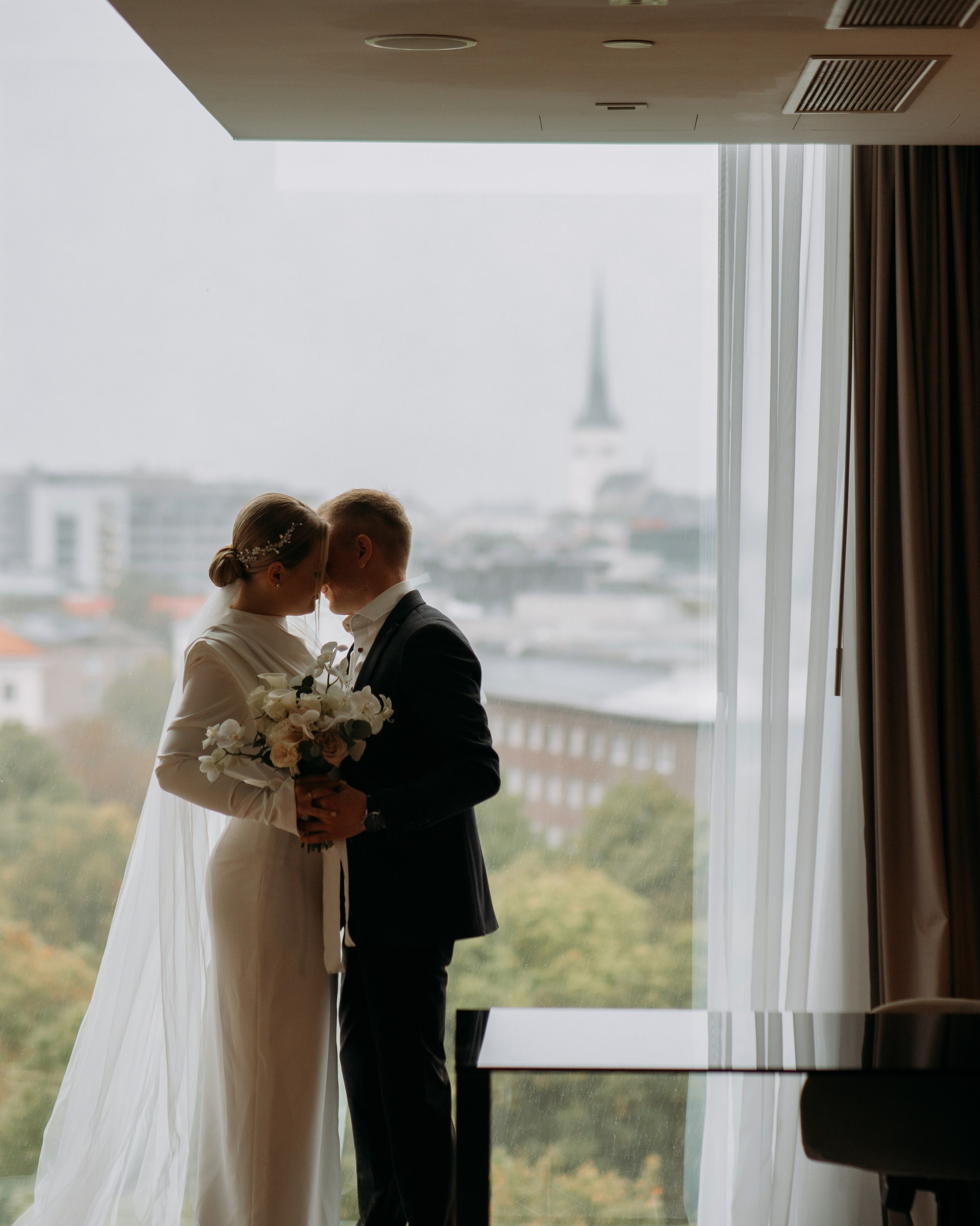 Свадебный фотограф в Таллине — нежный момент пары у окна в день свадьбы