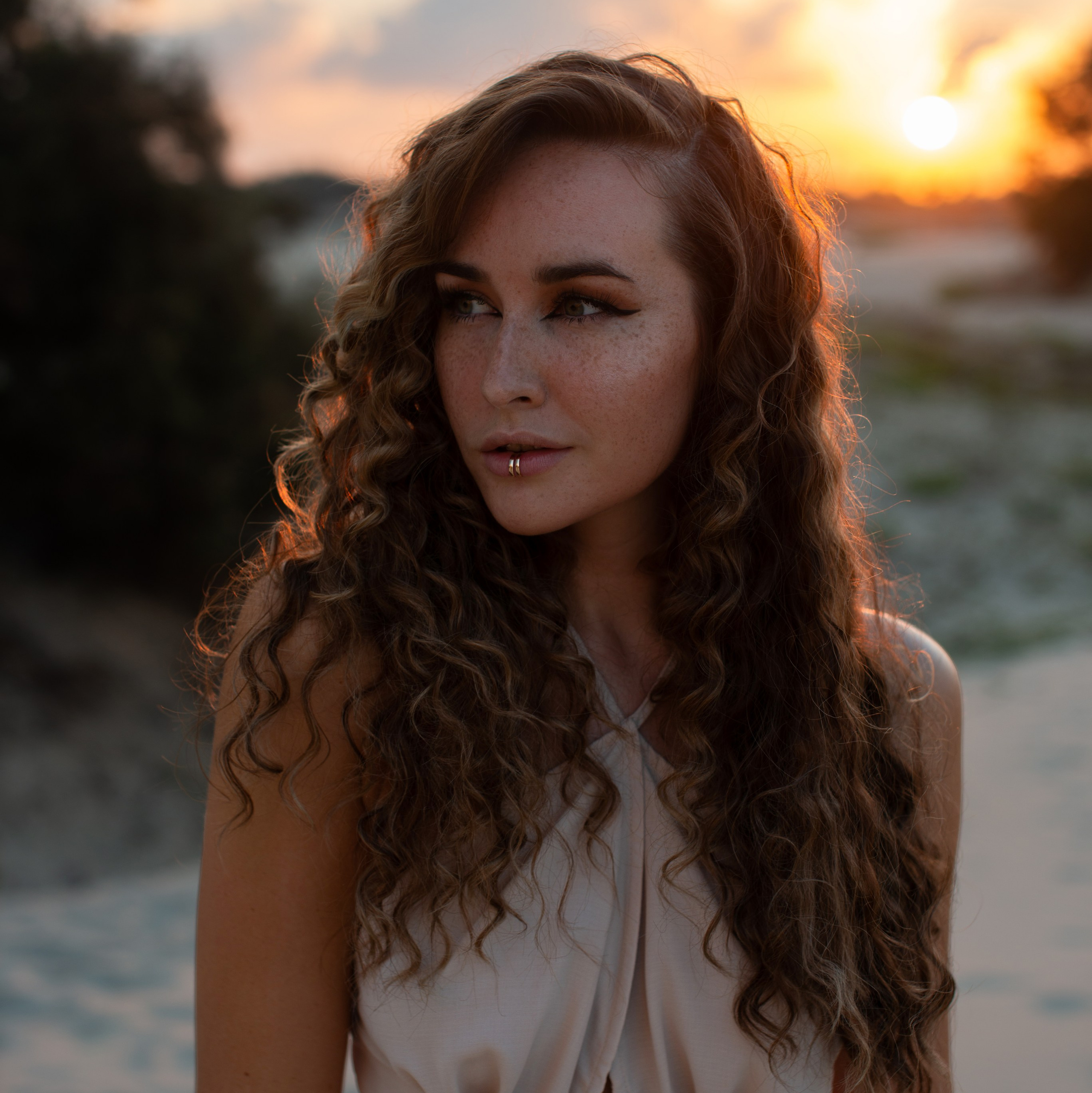 Portrait of a woman with long curly hair against a sunset background