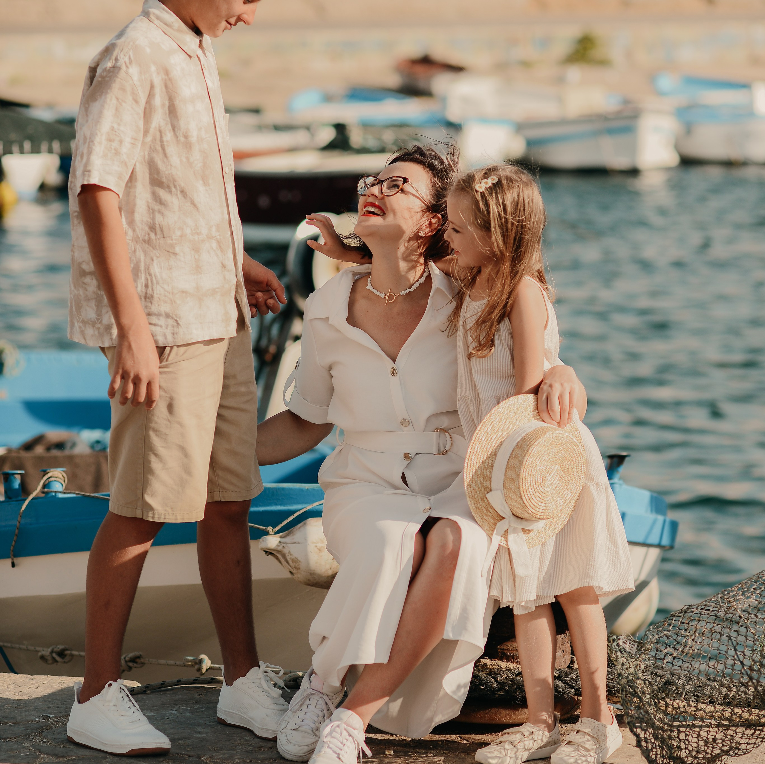 Mother with her son and daughter sharing a joyful moment by the boats during a seaside photoshoot in Monopoli