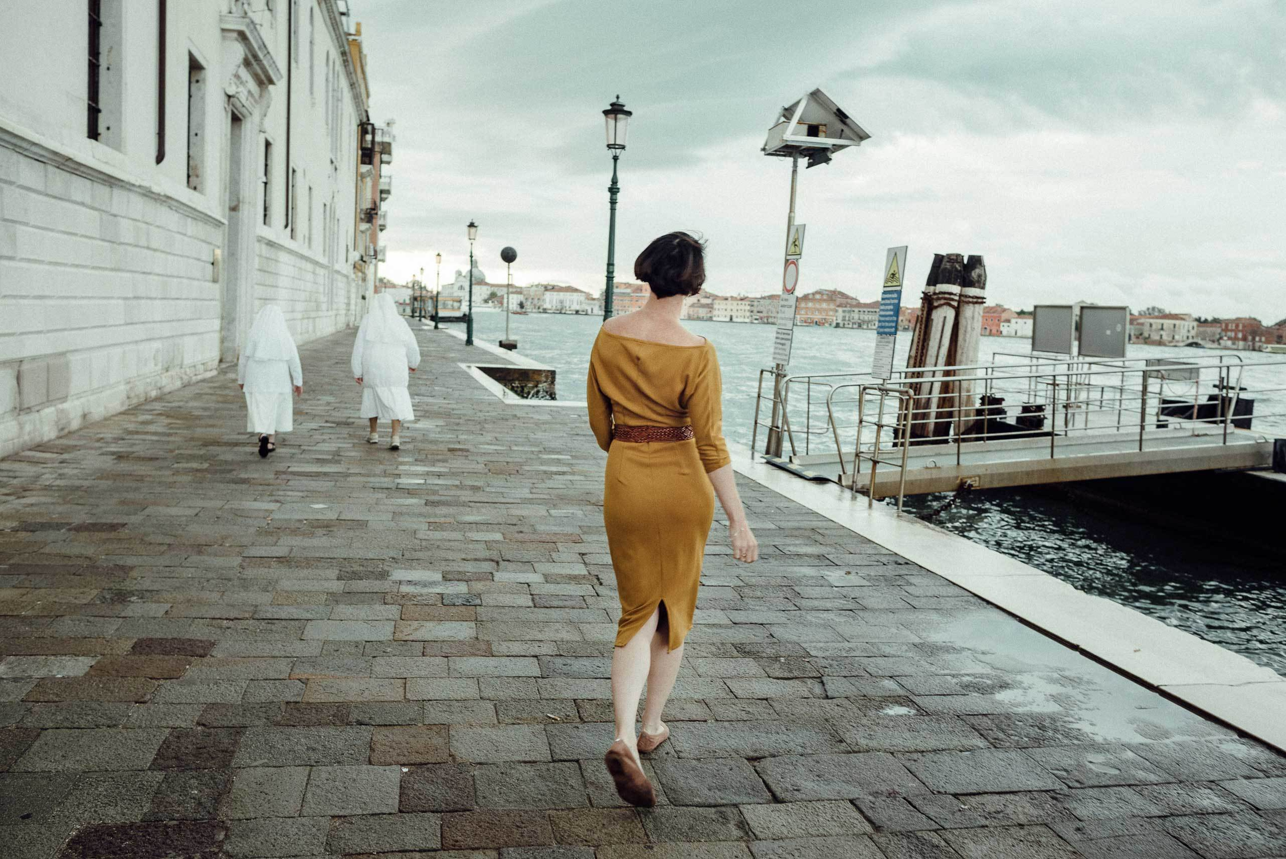 La donna con vestito giallo cammina in Venezia da sola.