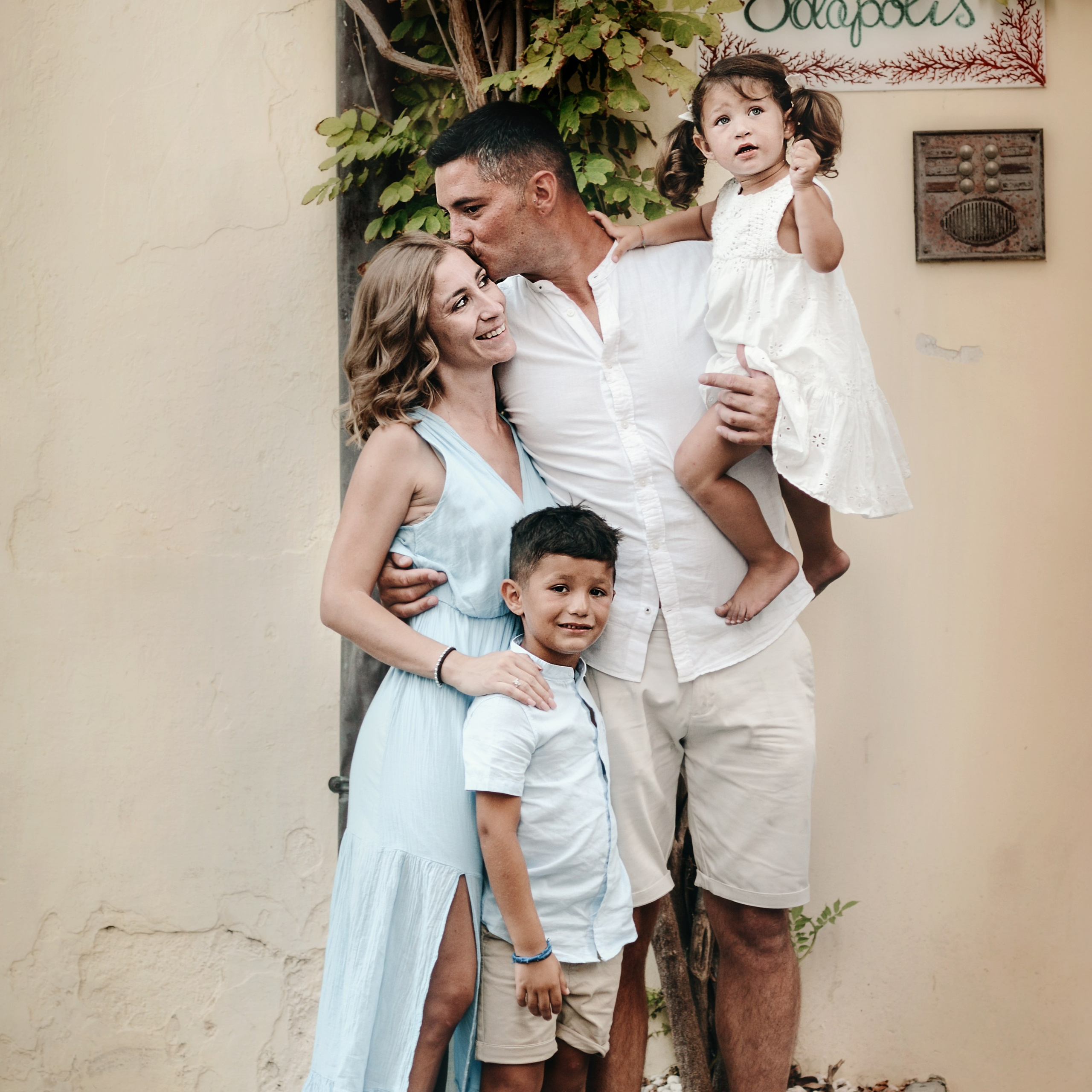 Emotional family photoshoot in Puglia — parents hugging their two children during a summer vacation session