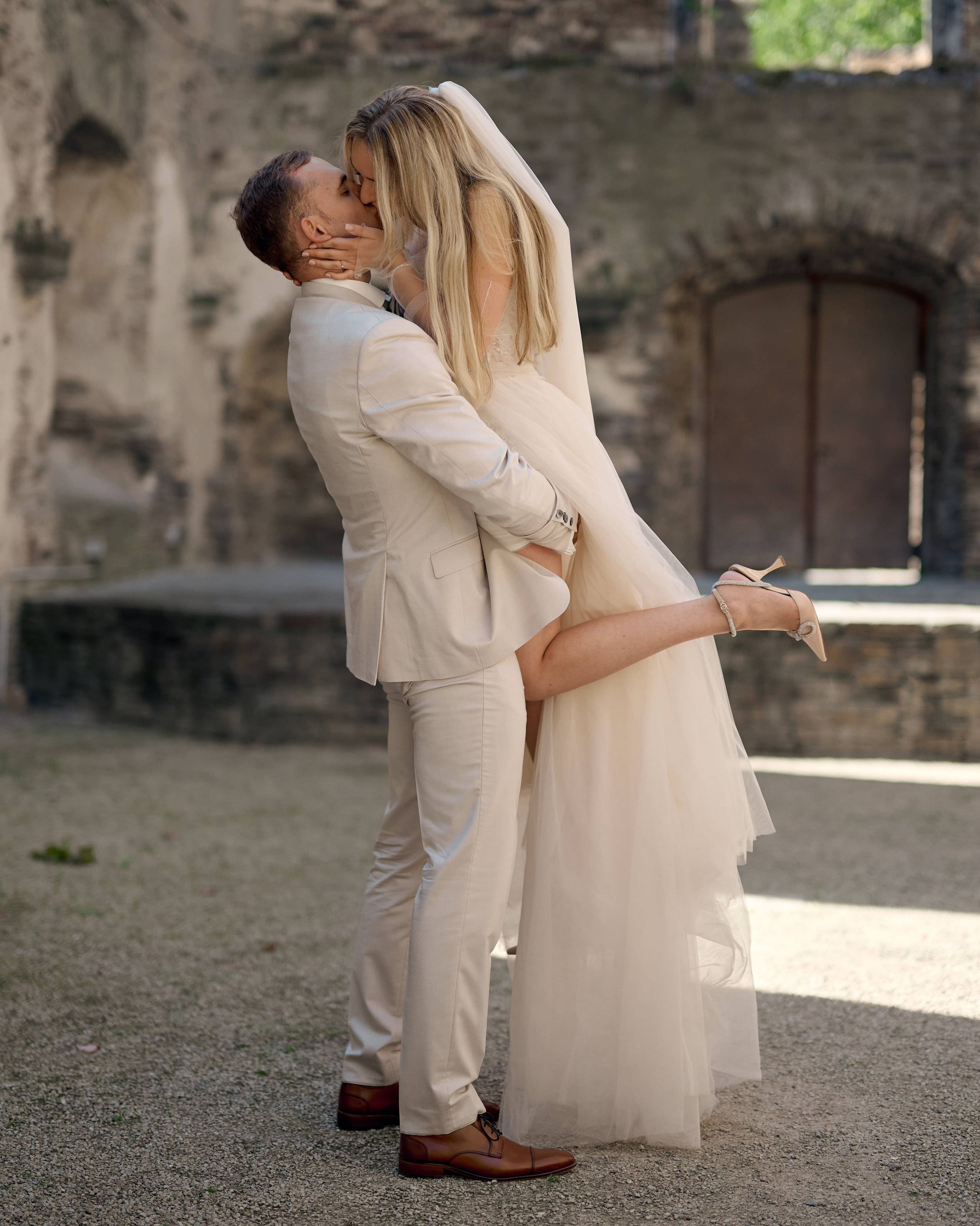 Bräutigam hebt seine Braut hoch und küsst sie liebevoll bei einem Hochzeitsshooting in einer romantischen Ruine nahe Bonn, fotografiert von Hochzeitsfotograf Alex Fetter.