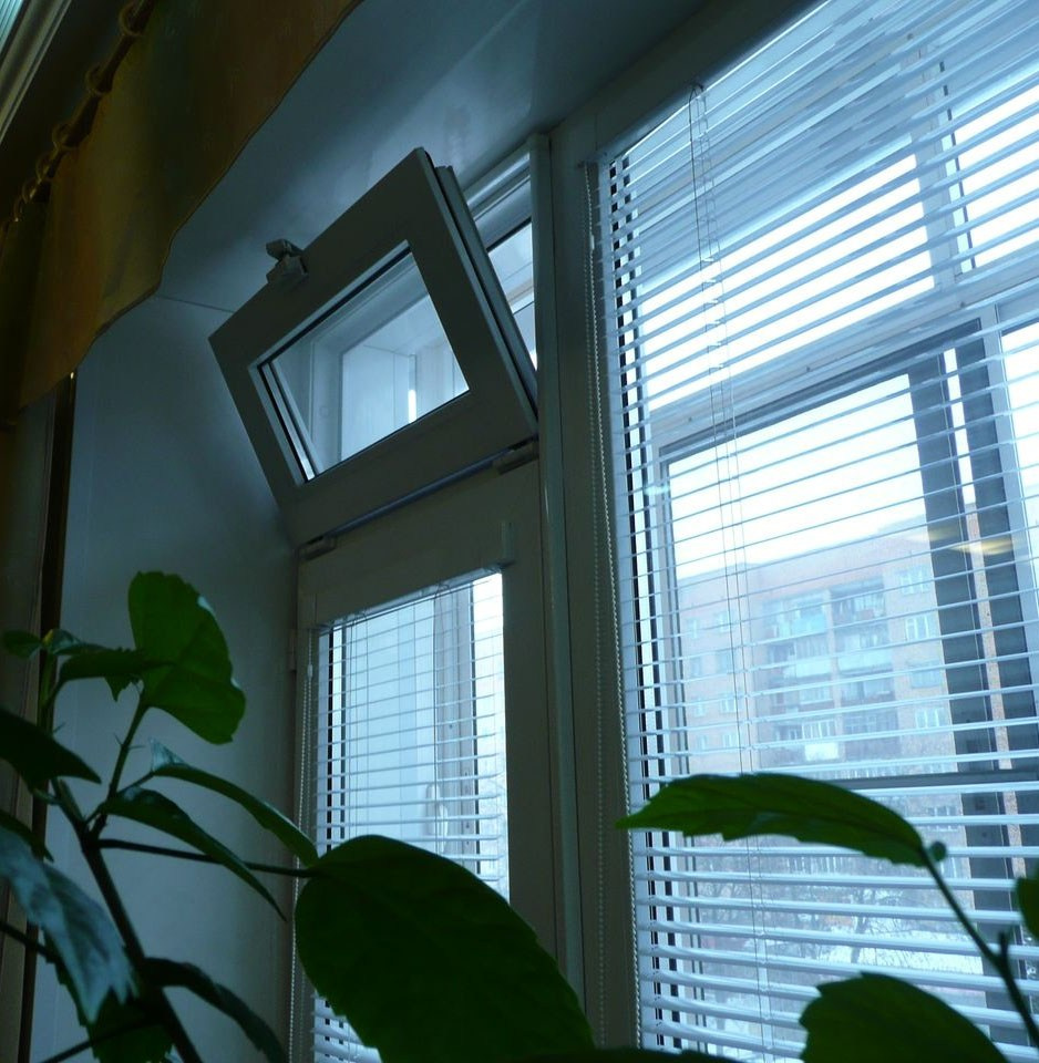 Пластиковое окно белого цвета с фрамужным типом открывания в левой части, и установленными на окно горизонтальными жалюзи.